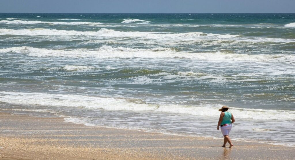 A lady walks barefoot along the surf's edge at Padre Island National Seashore near Corpus Christi, Texas