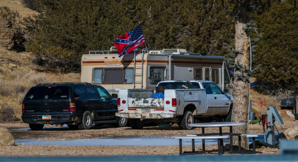 A vintage Fleetwood Bounder motorhome flying a blended Gadsden, US, and Confederate flag at an RV campground in Mt. Carmel, Utah