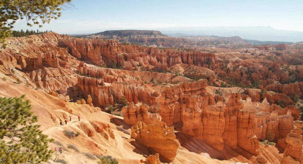 Hikers on a trail winding through thousands of orange and red hoodoo spires in Bryce Canyon National Park