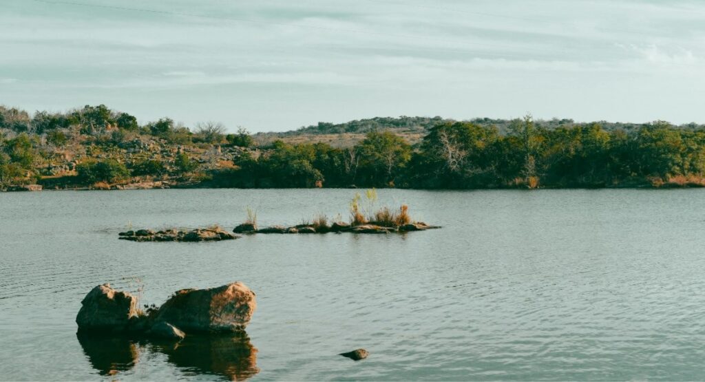 Rocky outcroppings rise from the calm waters of Inks Lake at Inks Lake State Park, Texas