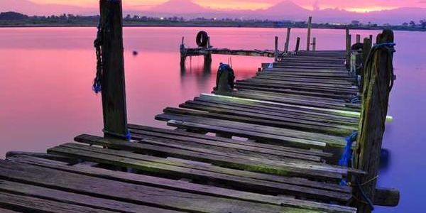 a wooden dock overlooking a body of water at sunset .