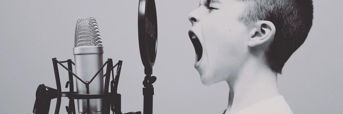 Boy singing into microphone in recording studio