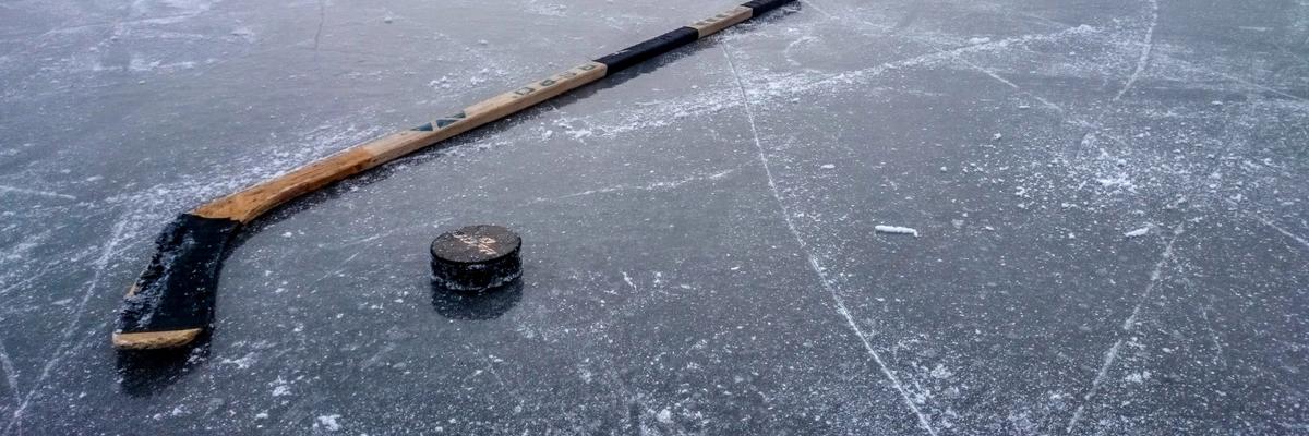 Ice hockey stick and puck on a frozen lake. Photo by Beppe Karlsson