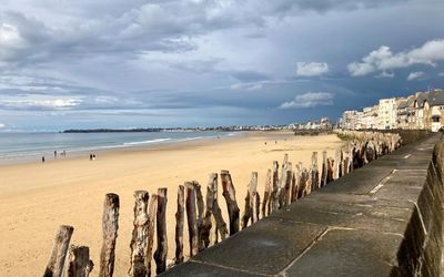 La plage du Sillon à marée basse à Saint-Malo, bordée par les remparts et les immeubles du front de mer, un cadre pour promener son chien en laisse hors saison