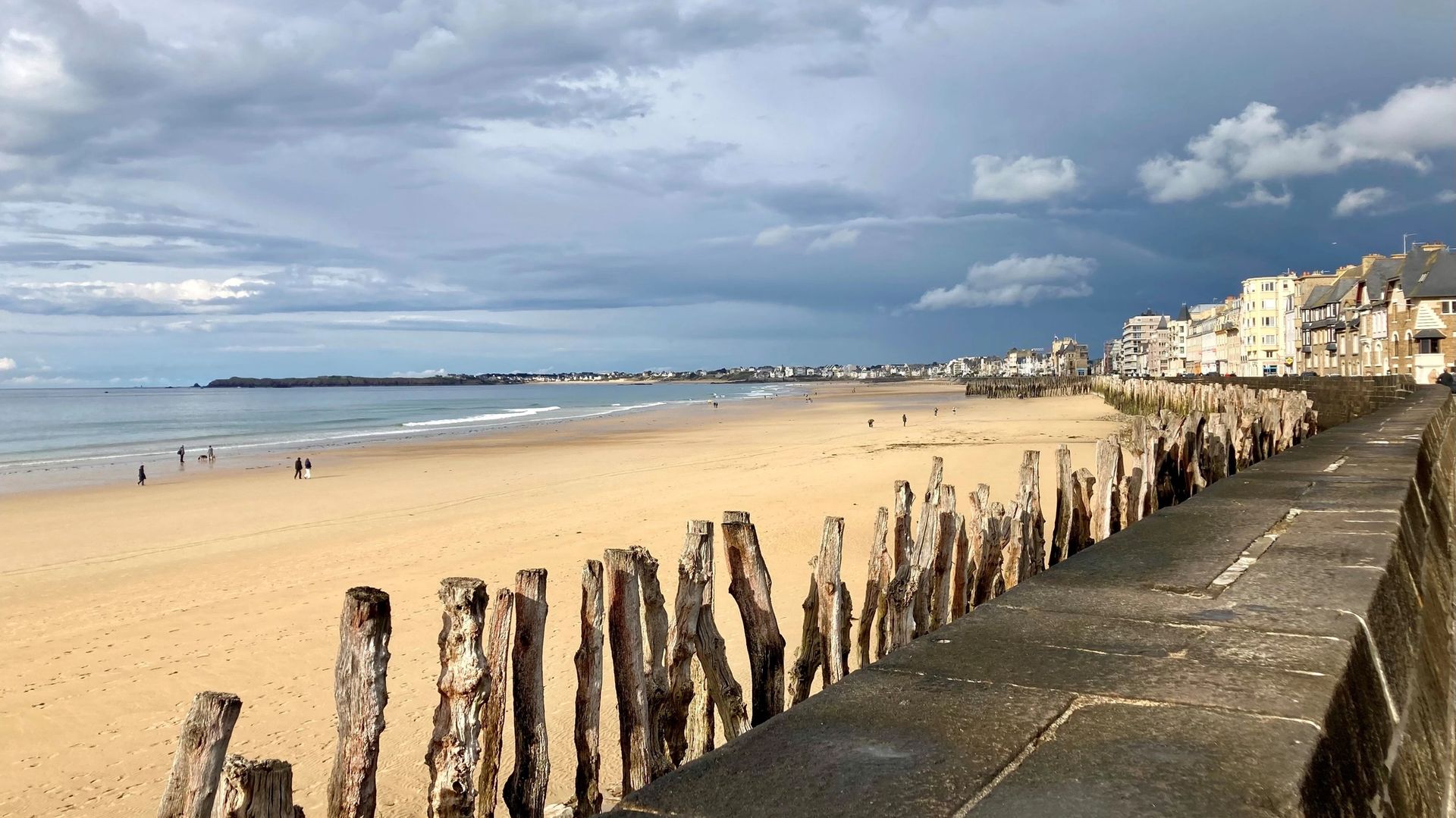 La plage du Sillon à marée basse à Saint-Malo, bordée par les remparts et les immeubles du front de mer, un cadre pour promener son chien en laisse hors saison