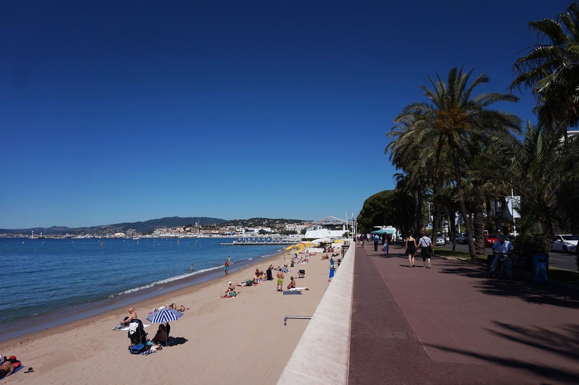 Plage de sable et promenade en bord de mer à Cannes, avec vue sur la baie et le massif de l'Esterel