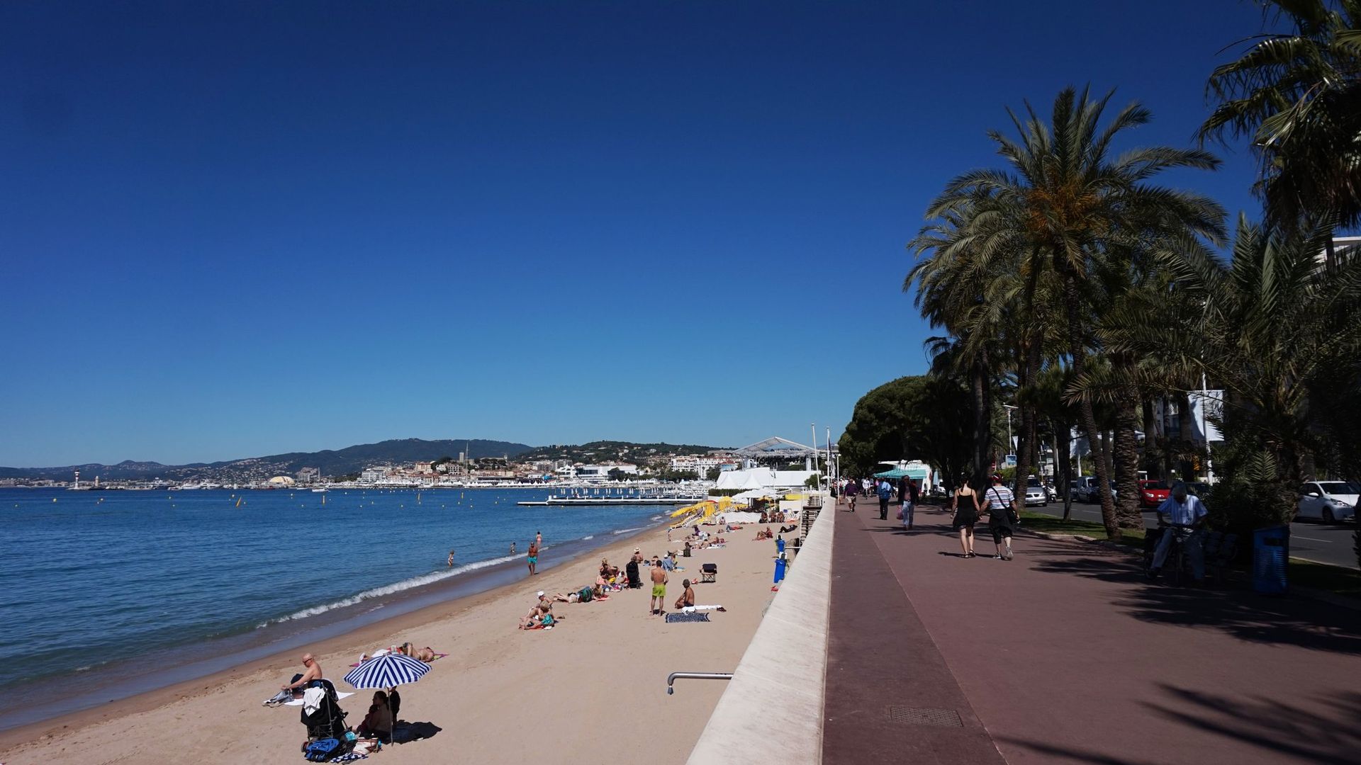 Plage de sable et promenade en bord de mer à Cannes, avec vue sur la baie et le massif de l'Esterel