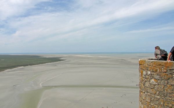 Vue sur la baie du Mont-Saint-Michel à marée basse, avec la digue menant au village, un parcours accessible aux chiens tenus en laisse