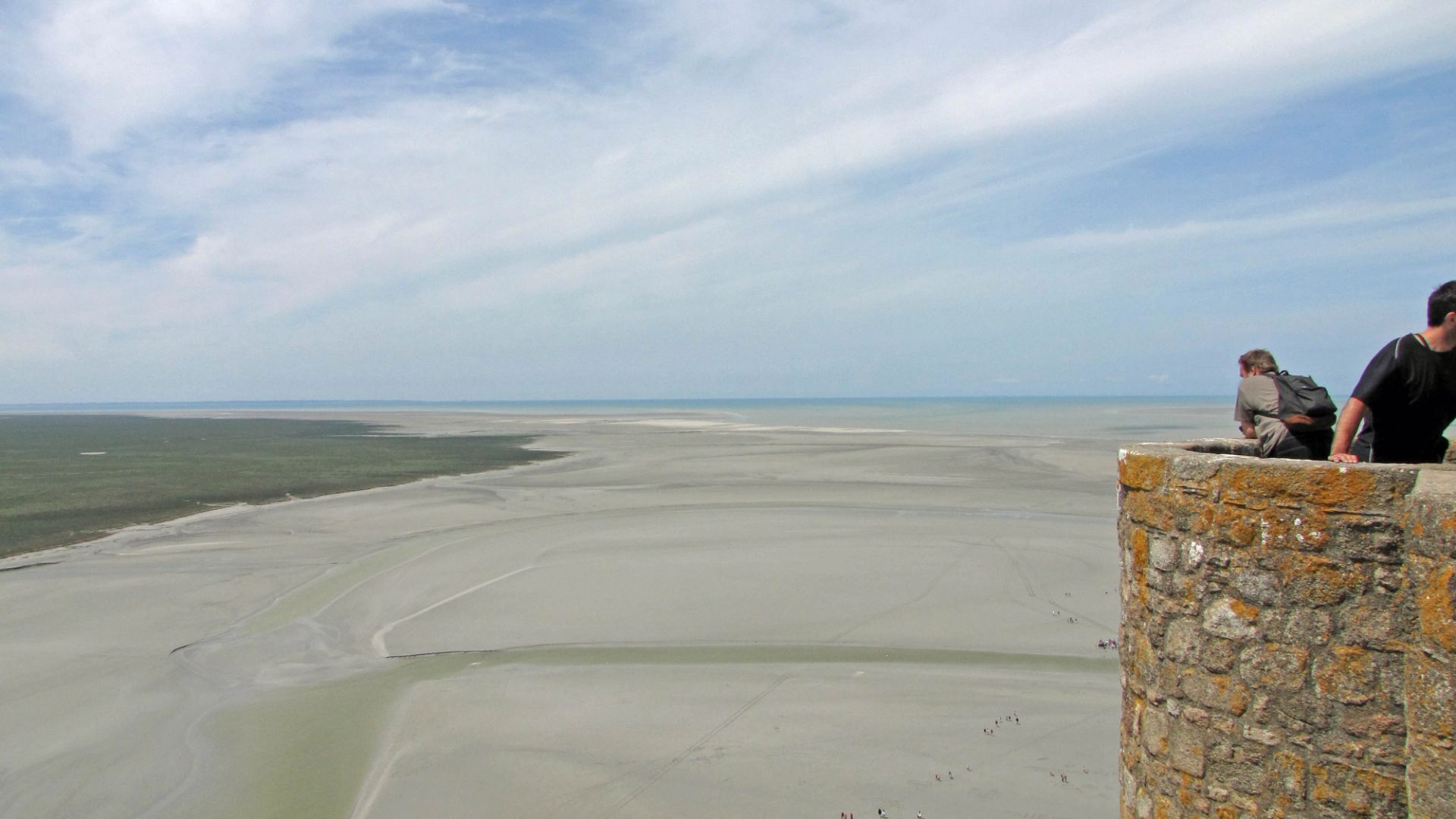 Vue sur la baie du Mont-Saint-Michel à marée basse, avec la digue menant au village, un parcours accessible aux chiens tenus en laisse