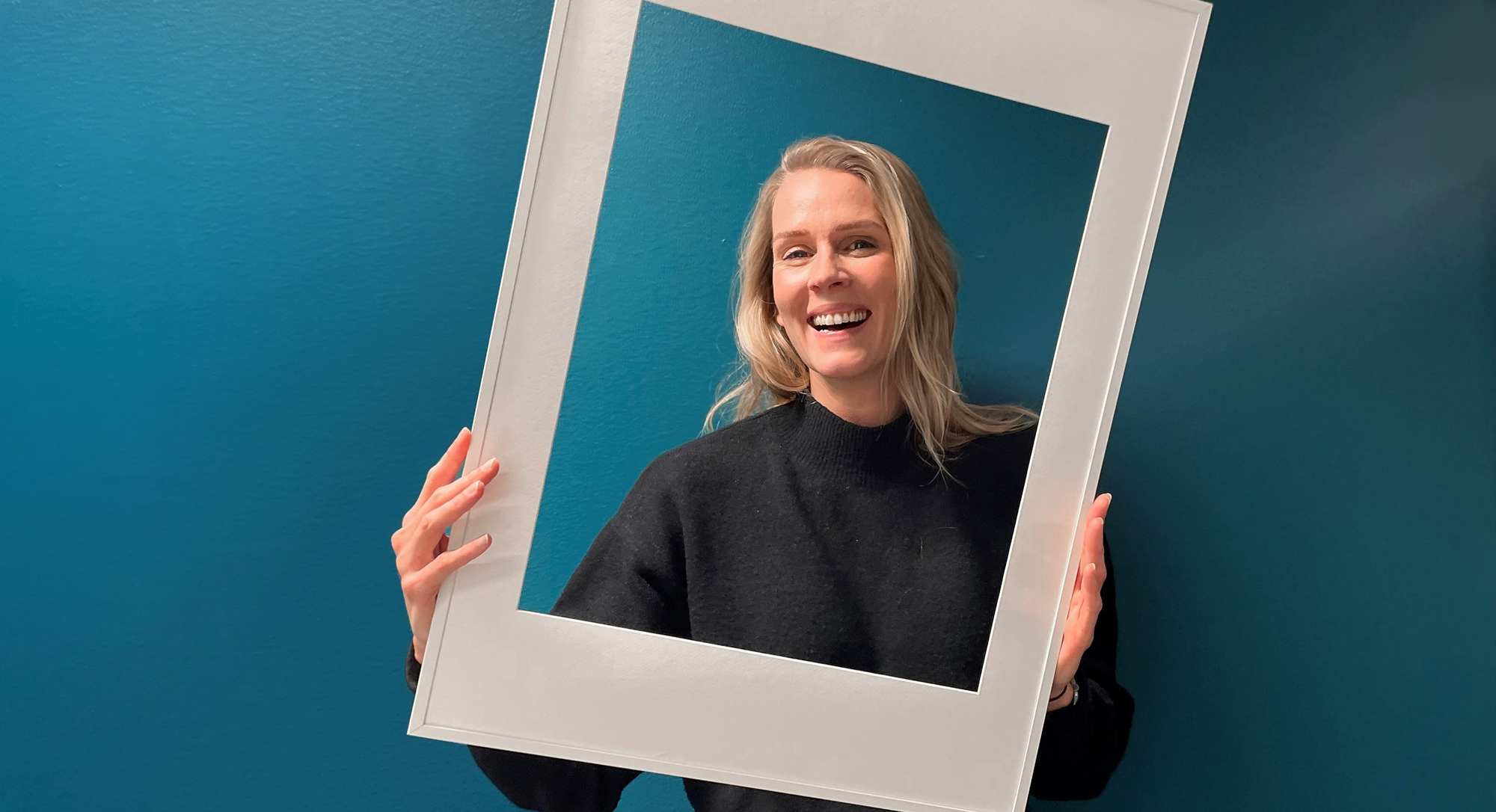 Therese som jobbar på Sappa ler mot kameran genom en vit fotoram.