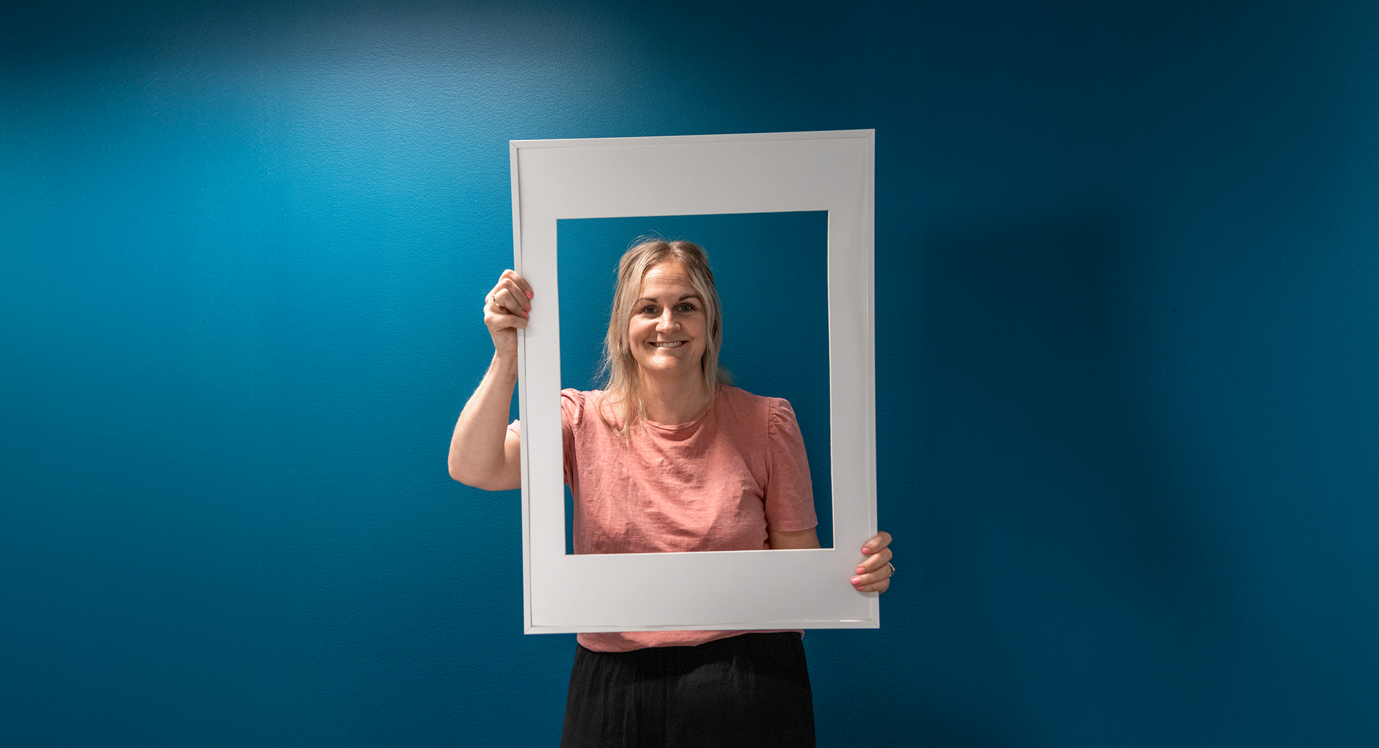 Marie som jobbar på Sappa ler mot kameran genom vit fotoram.