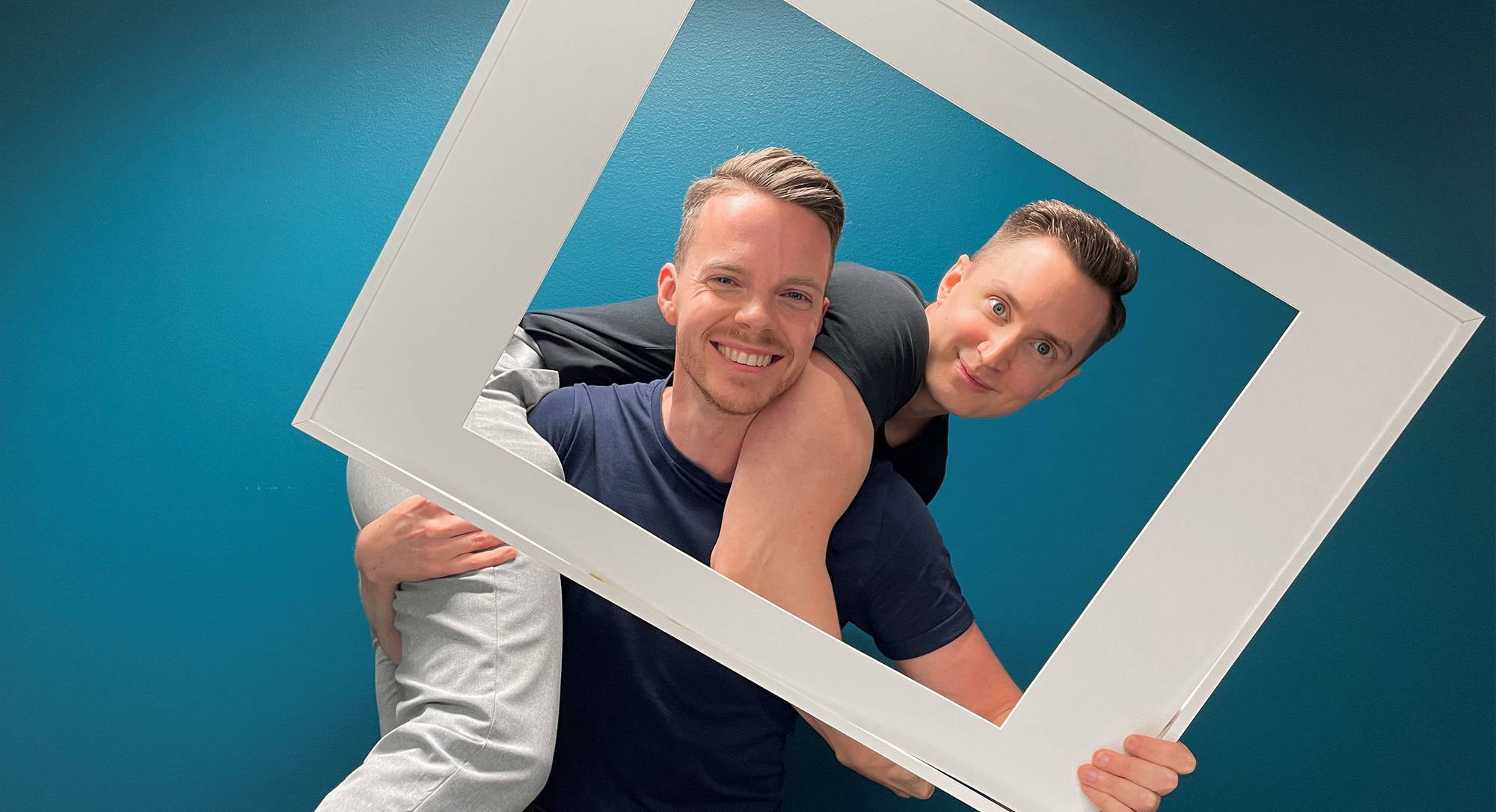 Simon och Jesper som jobber på Sappa ler mot kameran genom en vit fotoram.