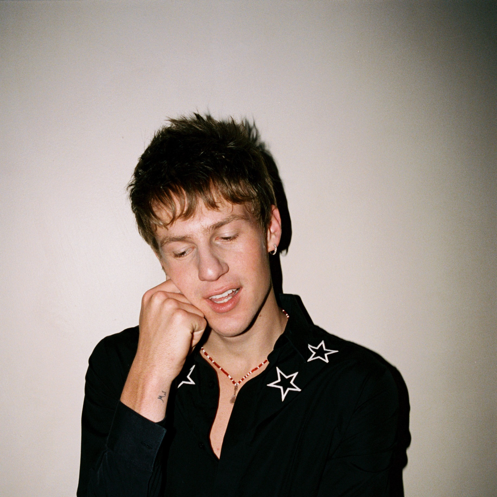 Malcolm Todd poses in a black jacket with star details against a pale background.