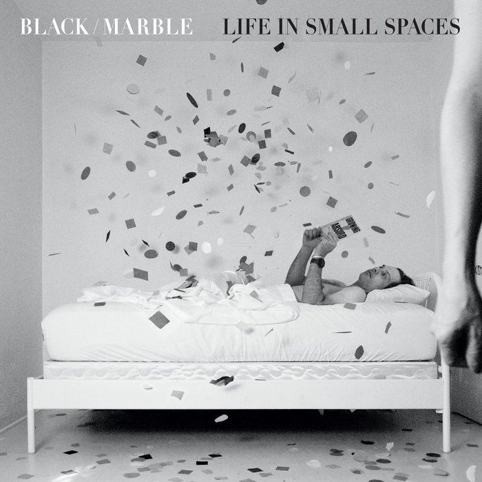 Black Marble Life in Small Spaces album artwork showing Chris Stewart seated in a sparse room with confetti.