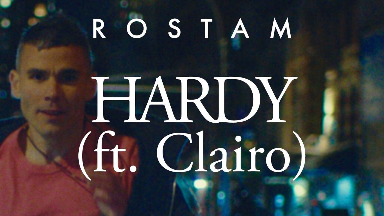 Rostam stands in warm light in the Hardy music video