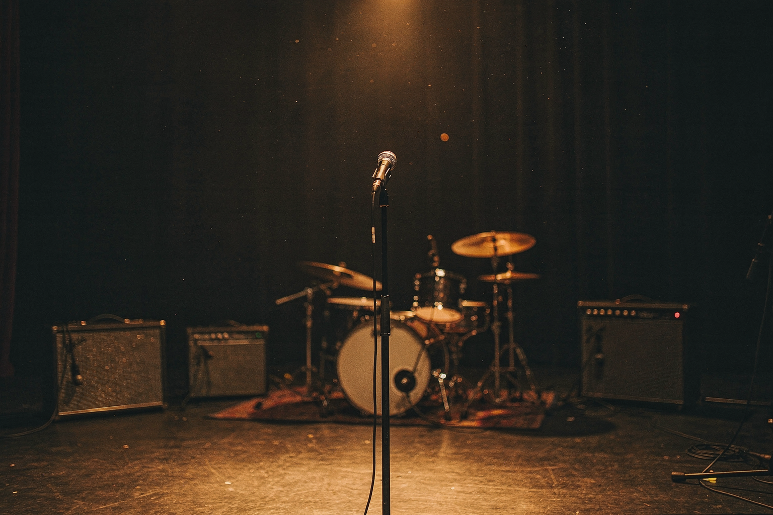 An empty dimly lit stage with a microphone stand for a slowcore starter guide.