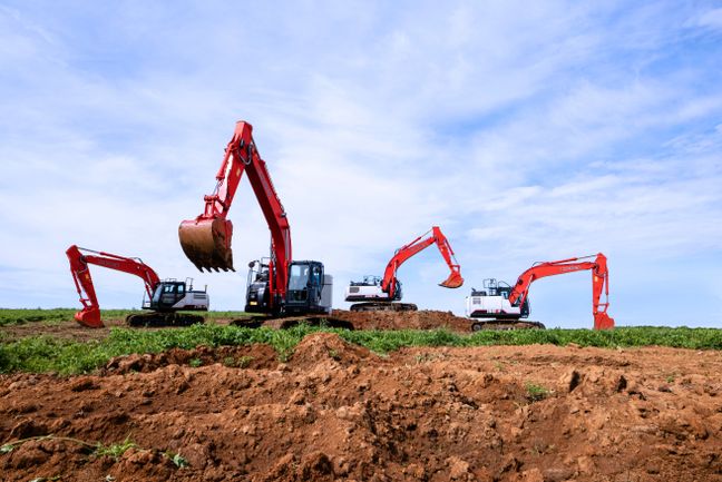 Four LBX excavators working under a blue sky