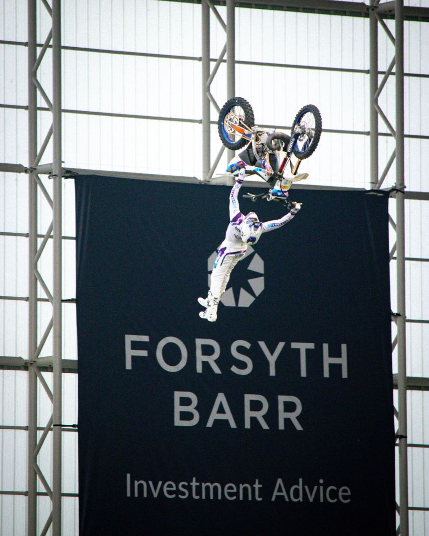 Motorcyclist stunt in front of Forsyth Barr logo in the stadium 
