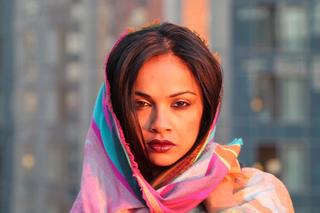 A headshot of a woman with a colorful pink and teal scarf around her head