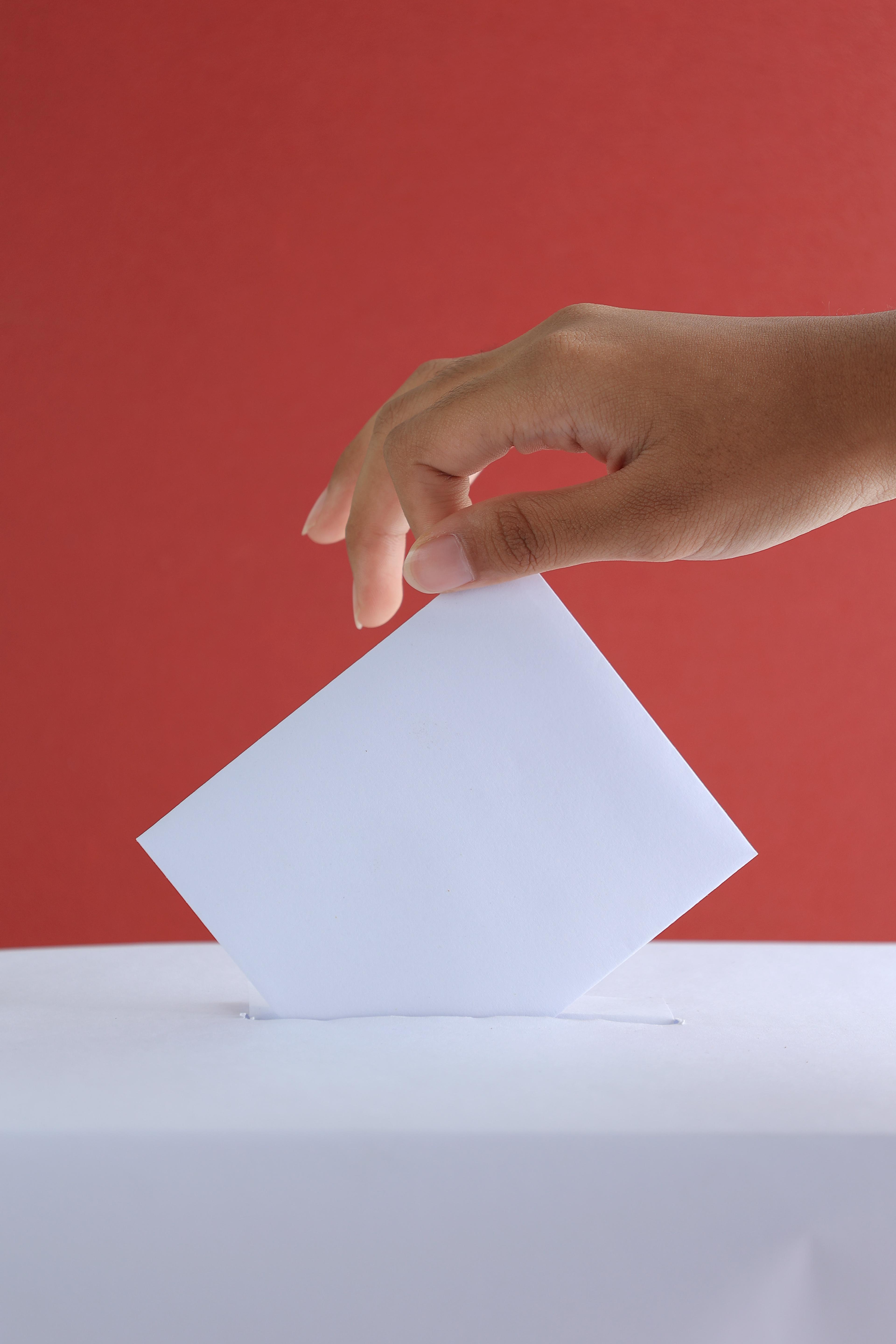 A person dropping their vote into a ballot box