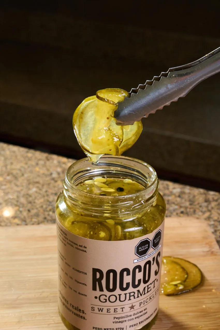 Pinzas sacando una rodaja de Sweet Pickles del frasco de Rocco's Gourmet