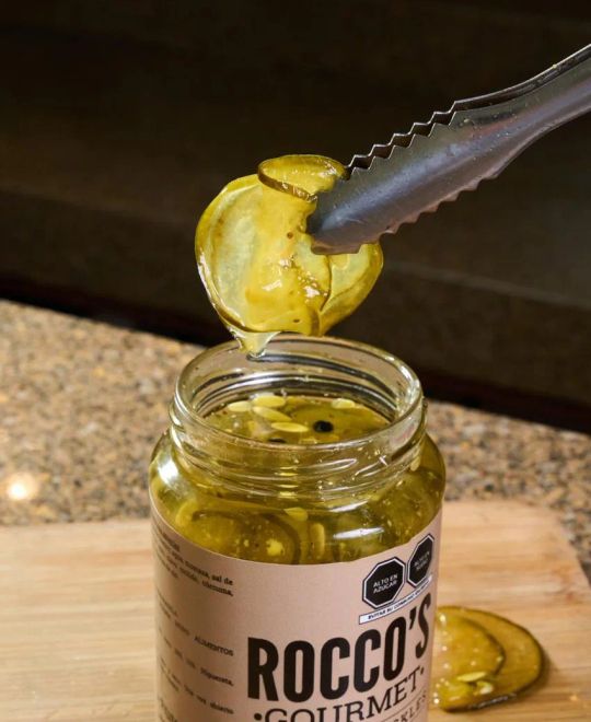 Pinzas sacando una rodaja de Sweet Pickles del frasco de Rocco's Gourmet