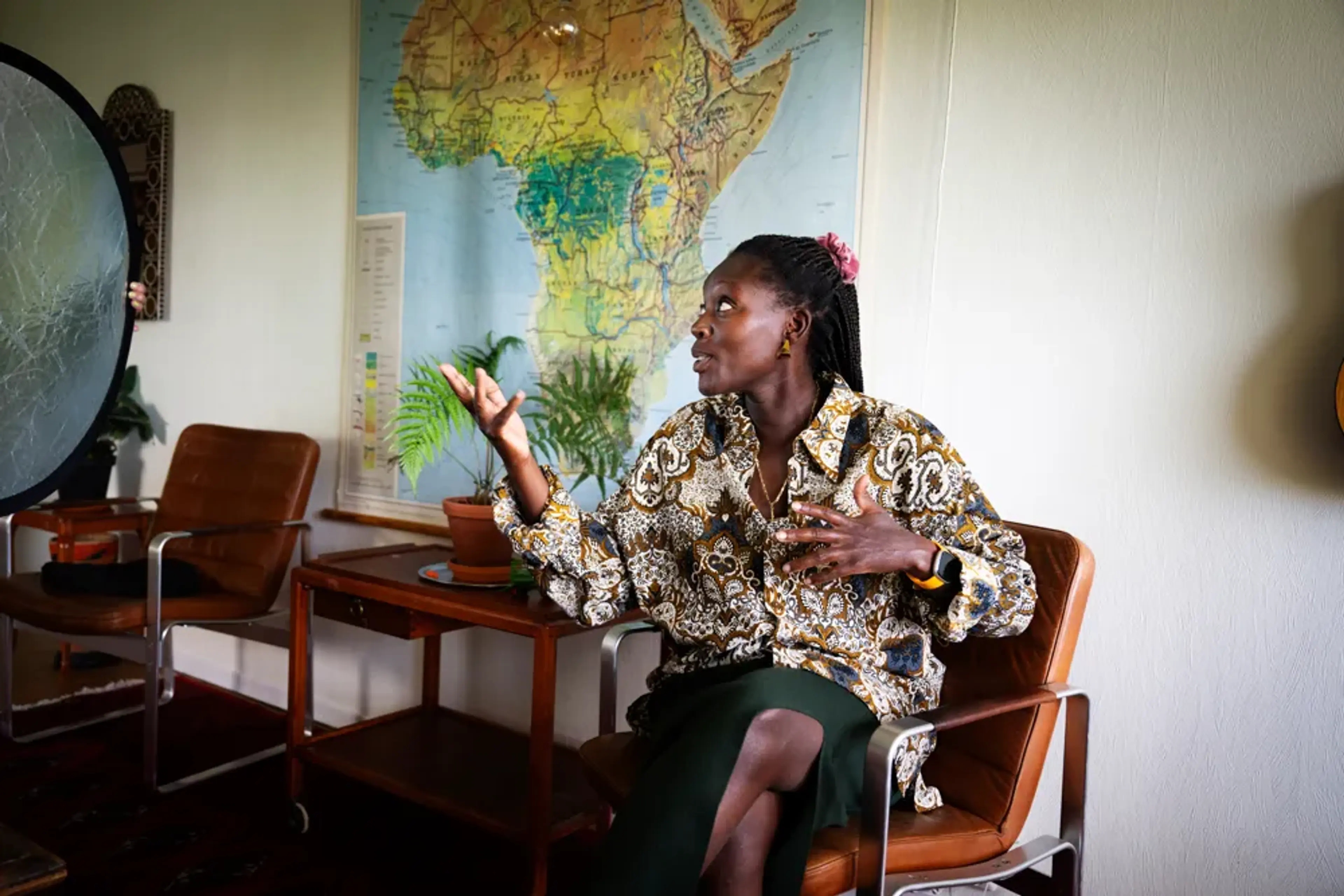 Silvia Kakembo sitter på en stol i ett ljust rum och talar engagerat under en intervju.