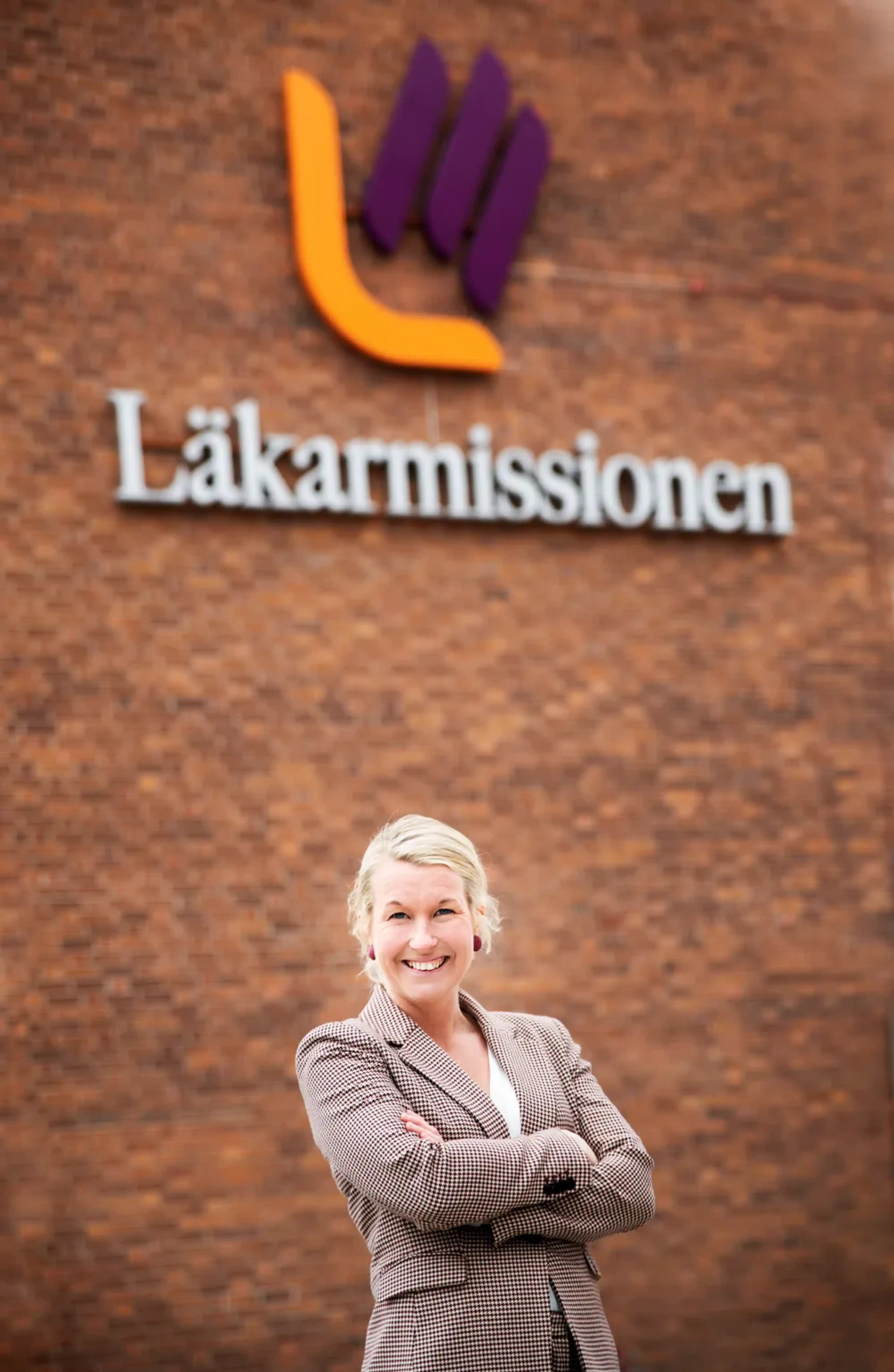 Josephine står utanför läkarmissionens huvudkontor med armarna i kors och ler mot kameran