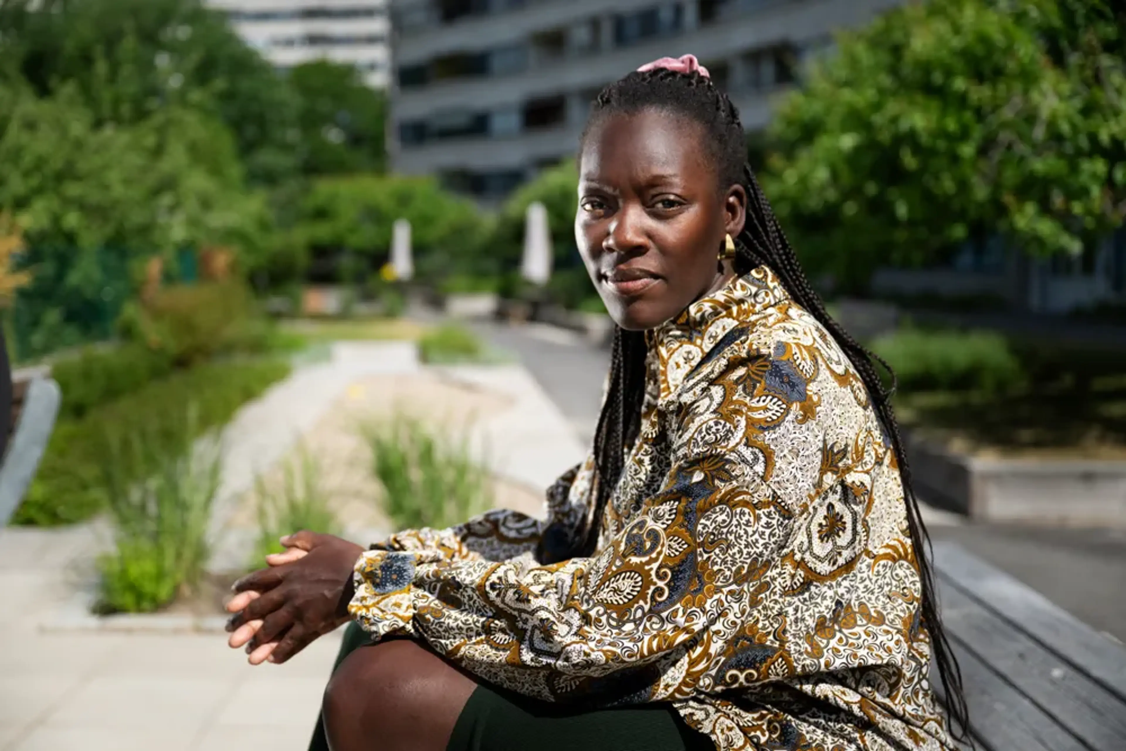 Silvia Kakembo sitter på en bänk omringad av grön natur