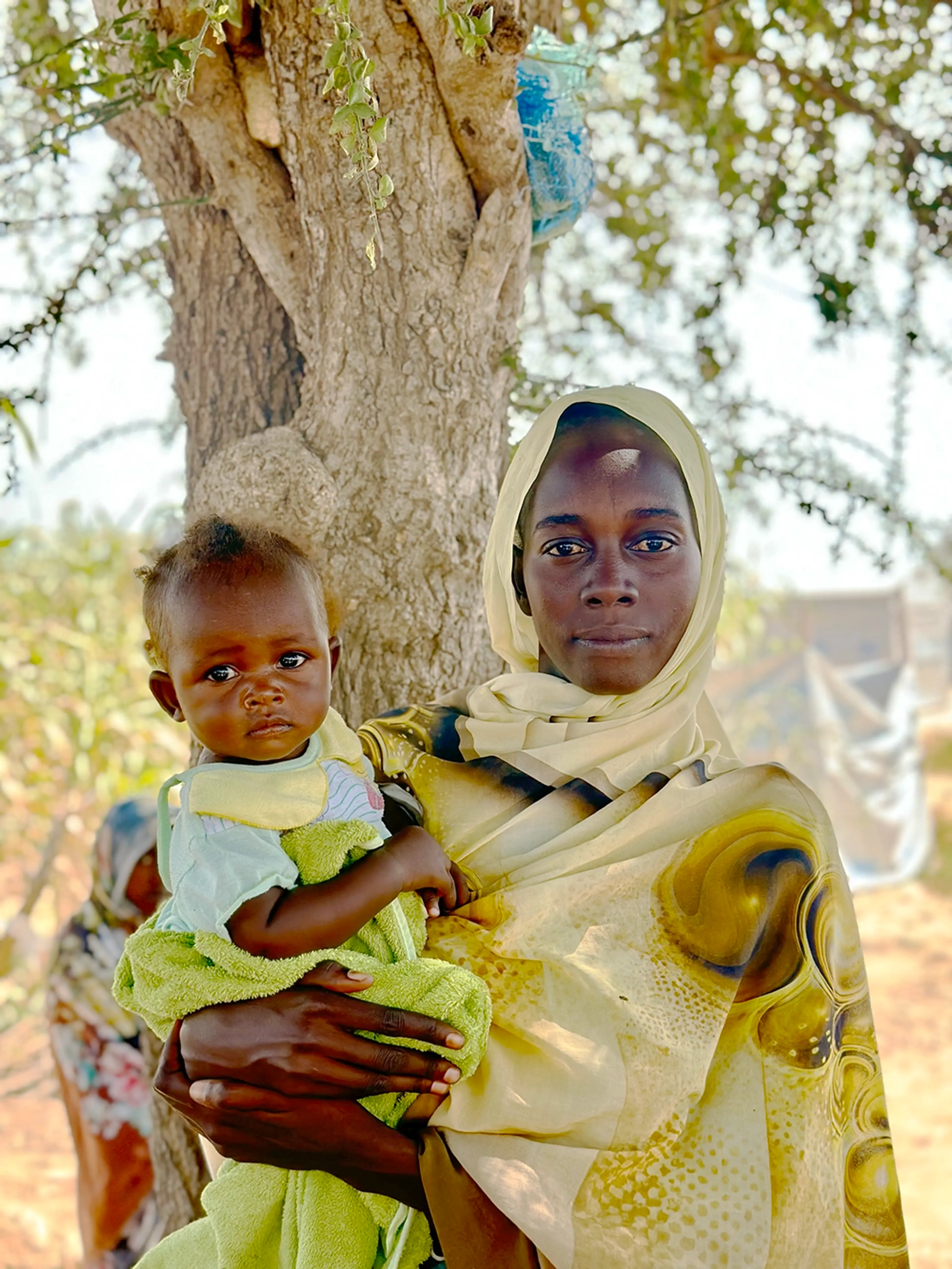 Kvinna i Sudan håller i ett litet barn på 1,5 år