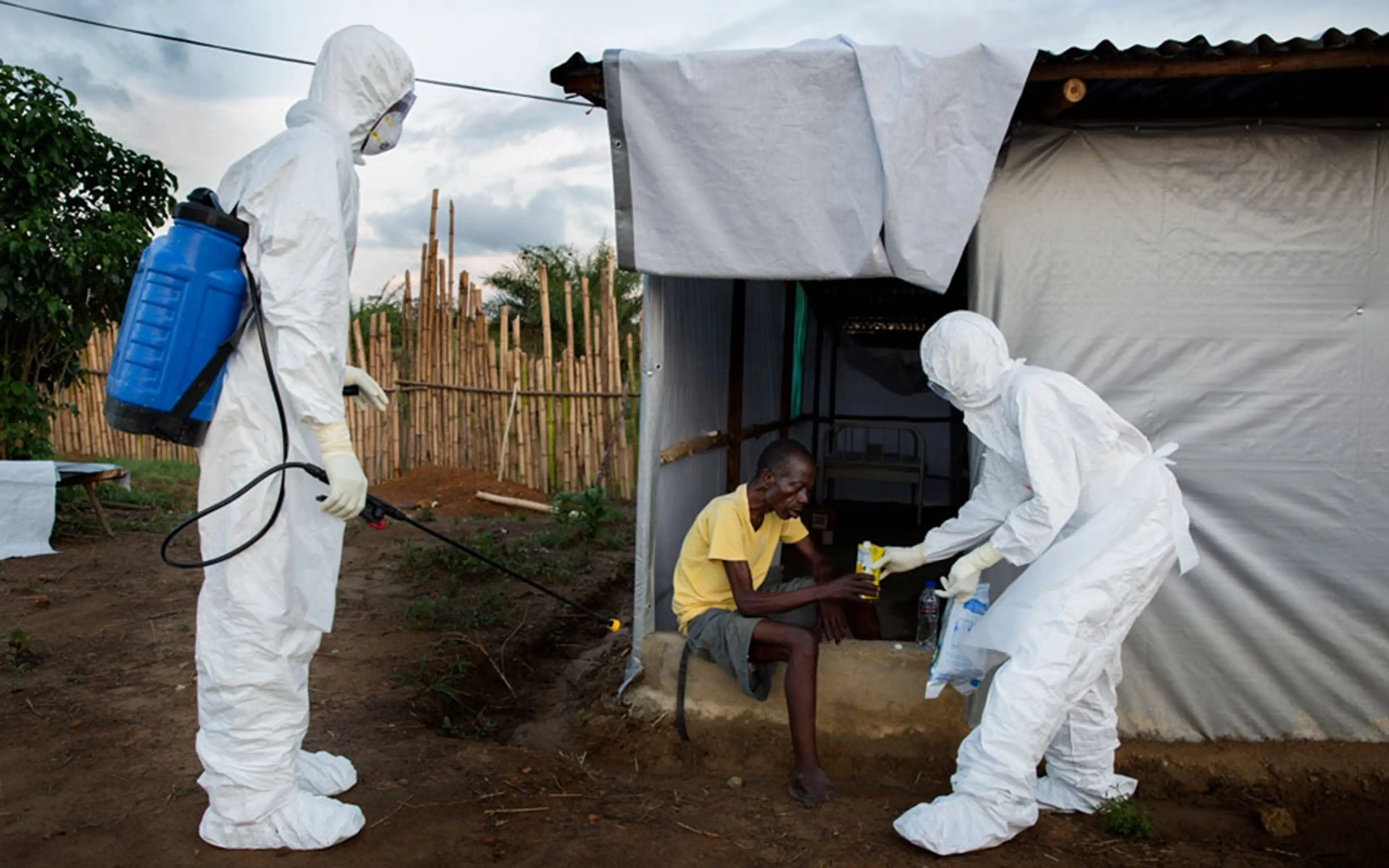 Människor i skyddsutrustning hjälper man med ebola