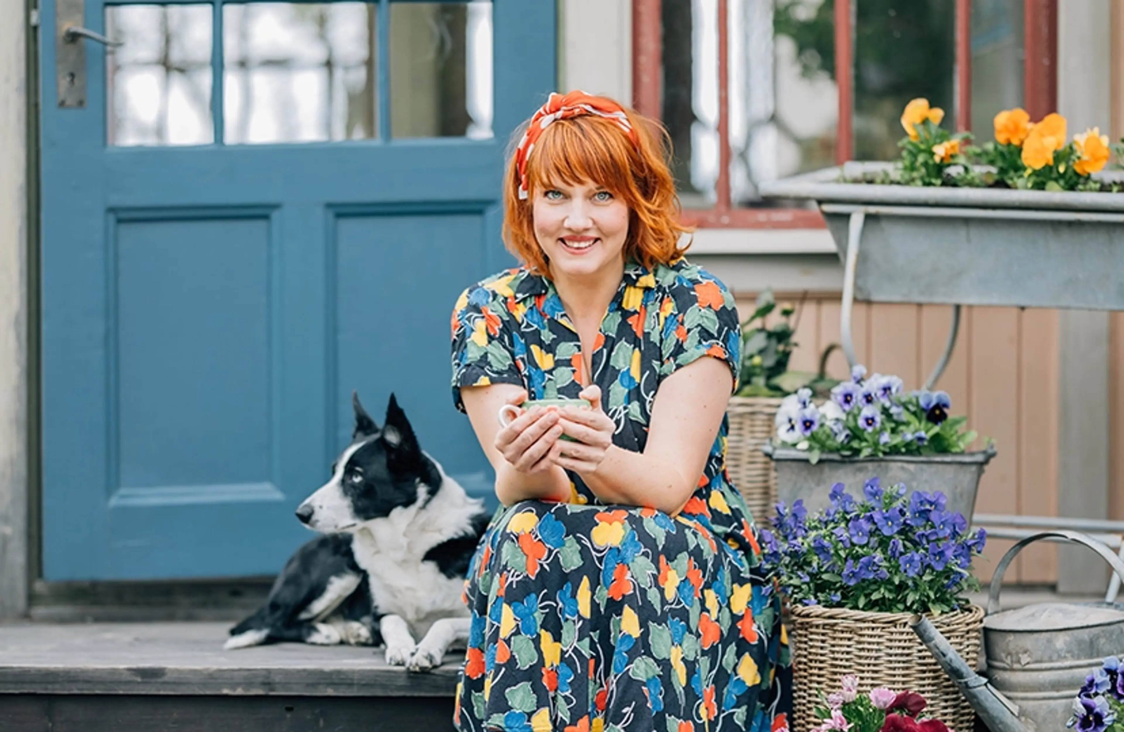 Clara Lidström sittande på trappa utanför hus tillsammans med hund och blomkrukor