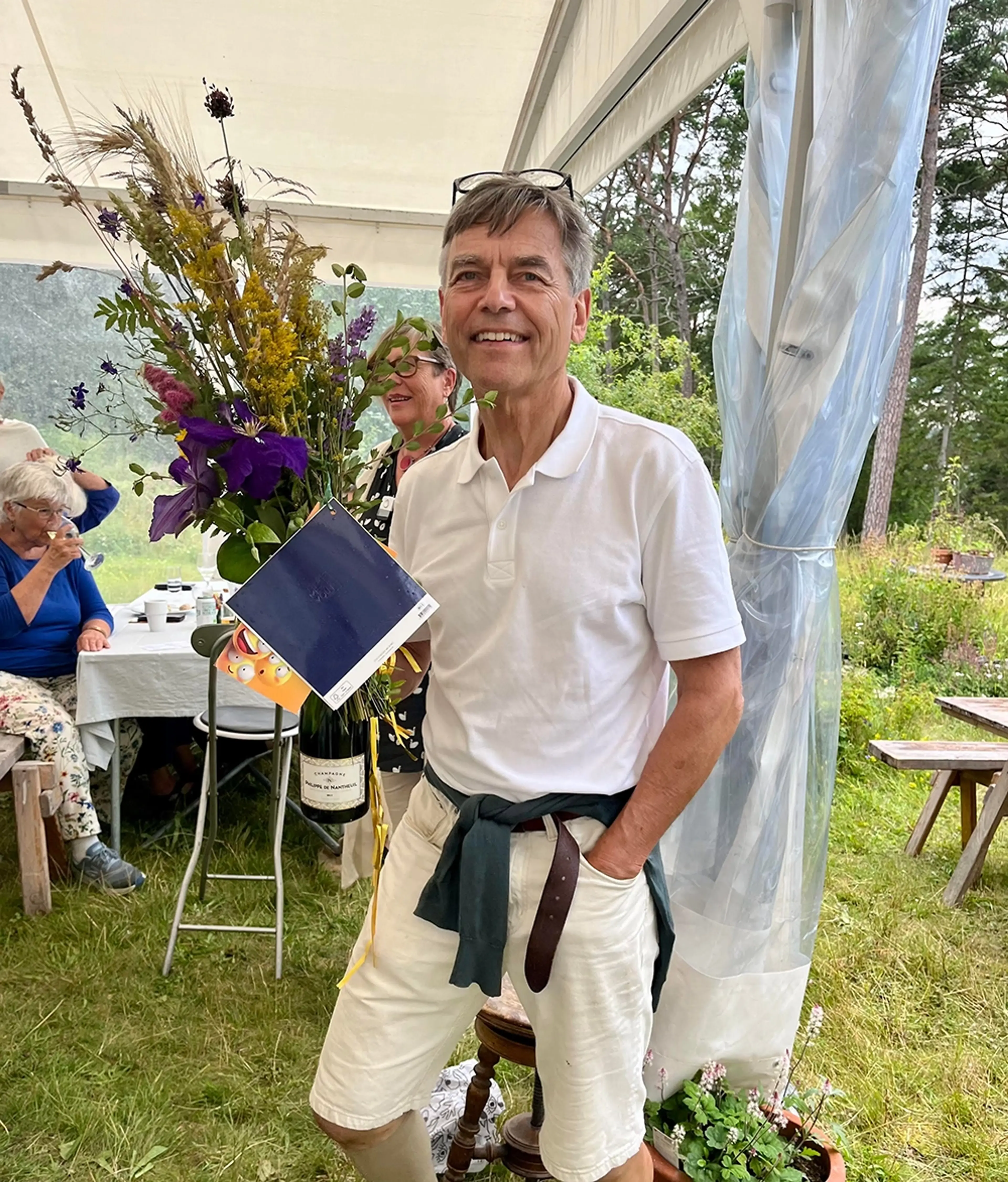 Hans står med blommor i handen 