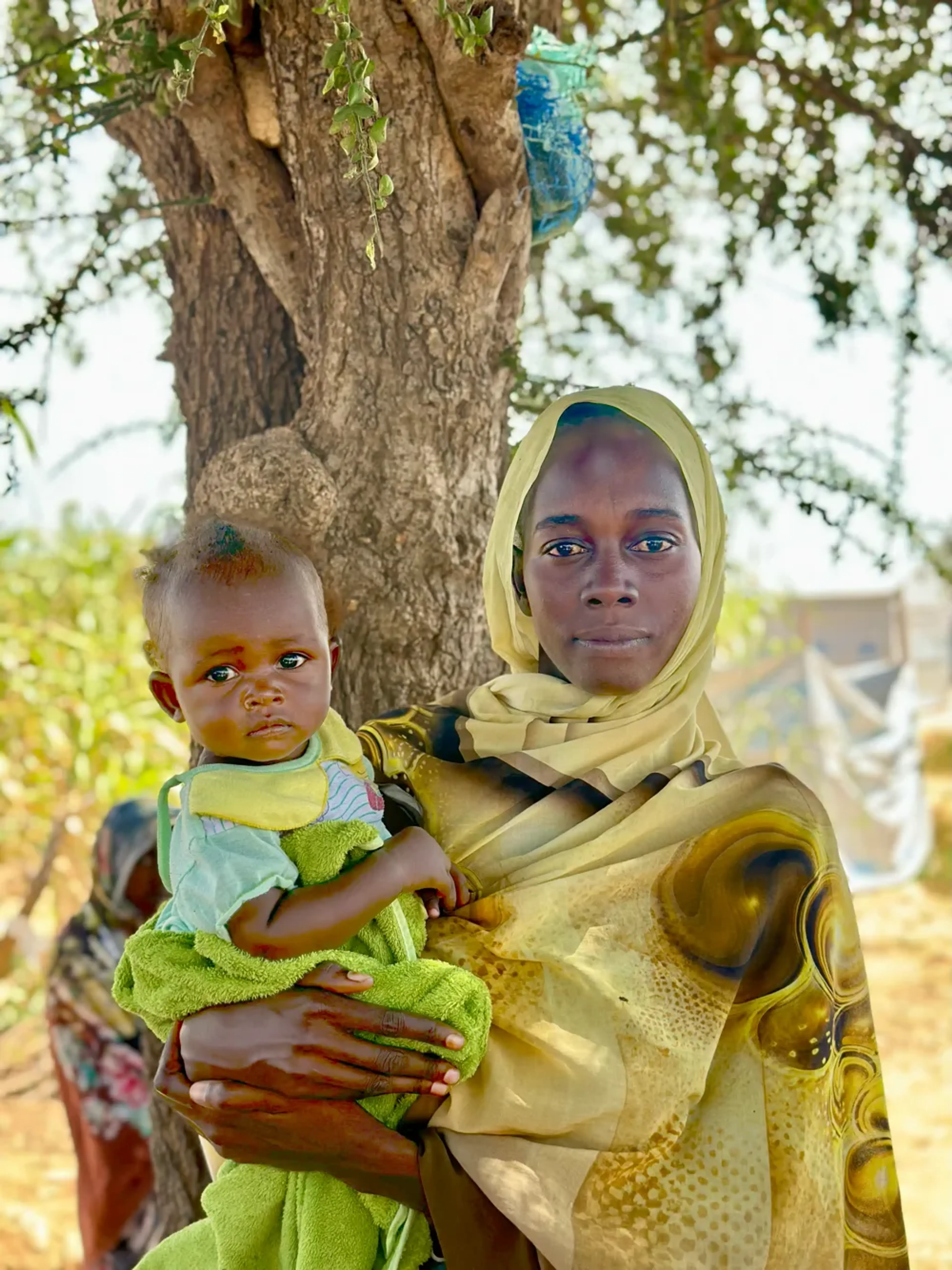 Kvinna i Sudan håller i ett litet barn på 1,5 år