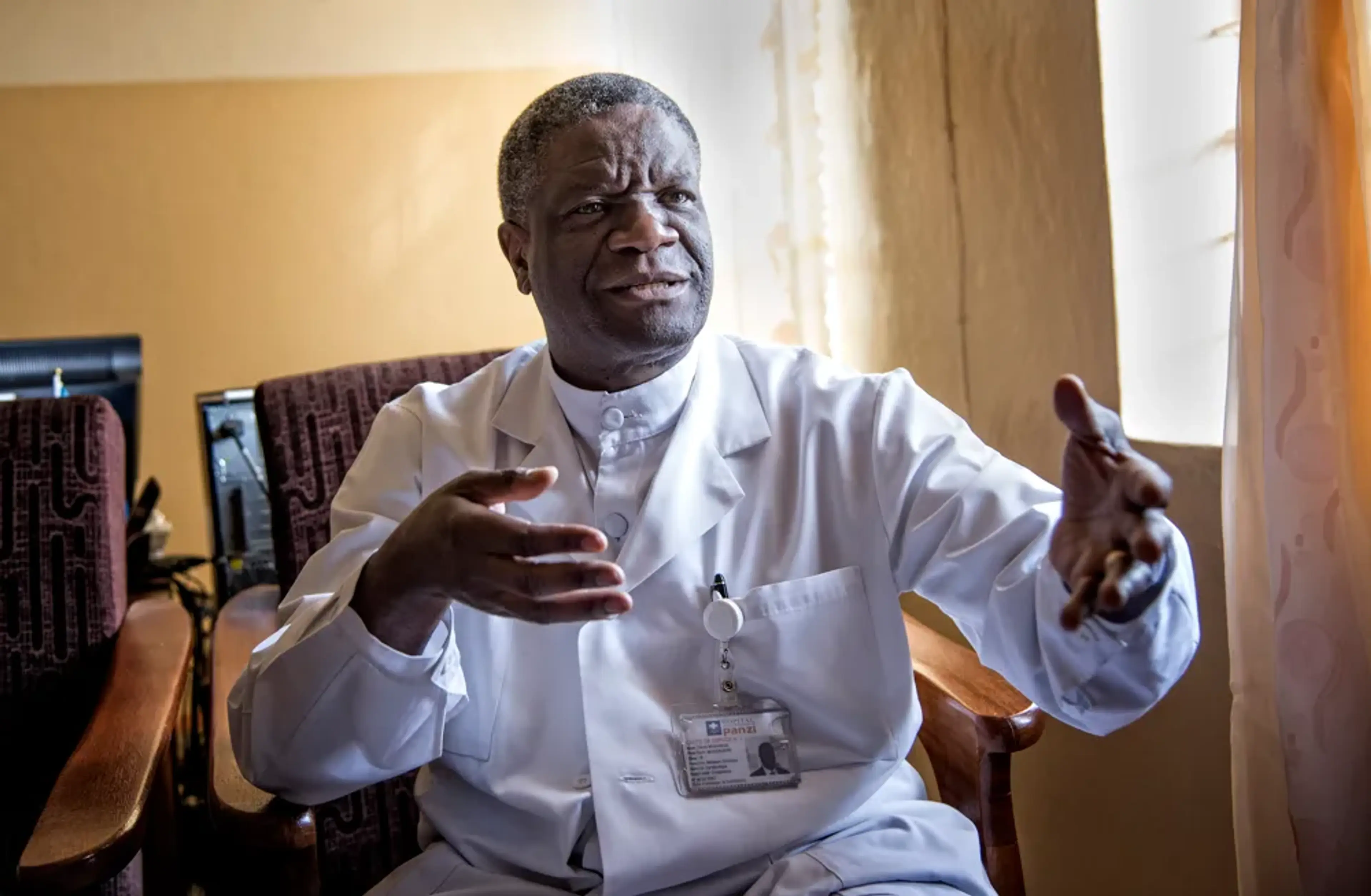 Denis Mukwege sitter på en stol i sin läkarrock och pratar samtidigt som han gestikulerar med händerna