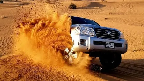 4x4 vehicle driving over golden sand dunes in the Qatar desert near the Inland Sea
