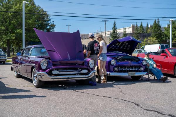 Two purple antiques with their hoods popped open. 
