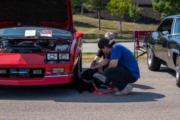 Red 80's Camaro with a guy petting a dog. 