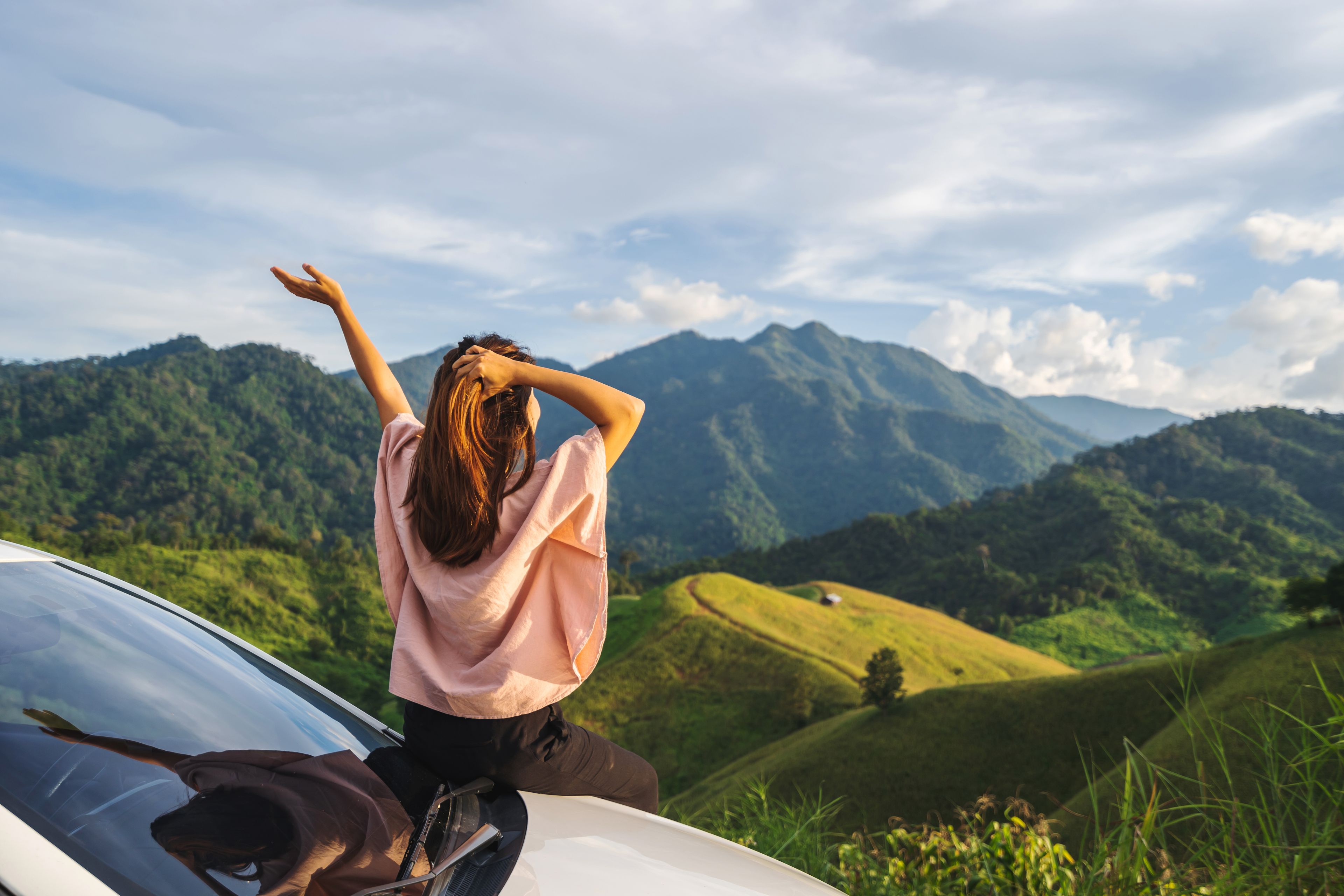 Girl with arm up staring at hills