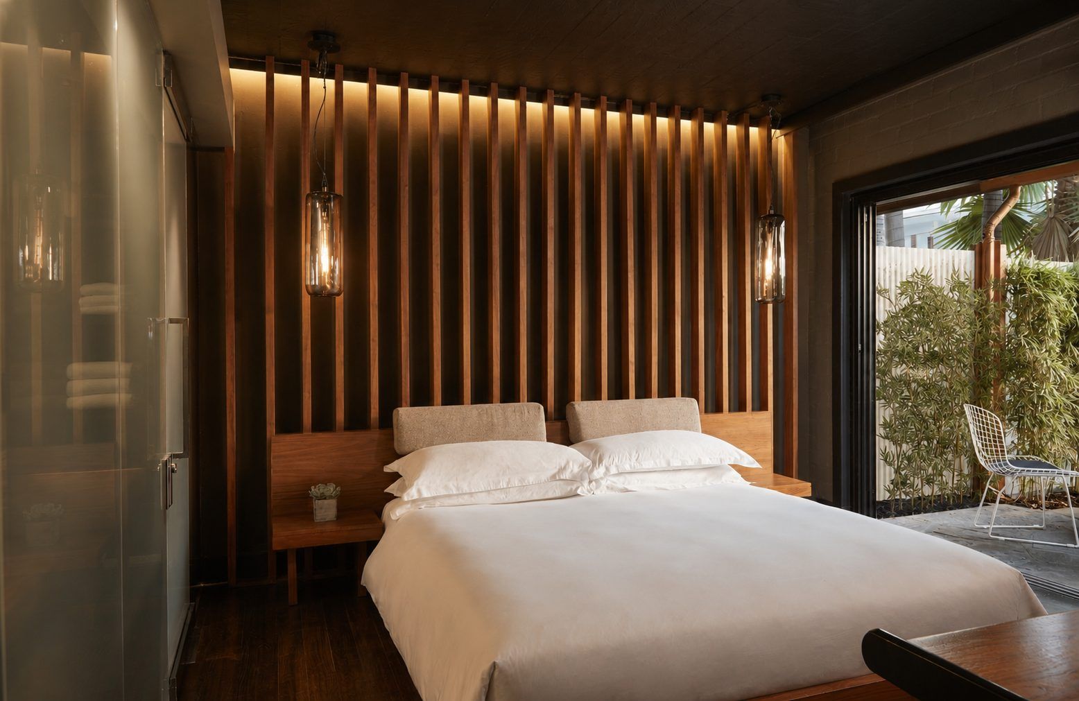 A hotel room with a large bed, a window, and a chair.