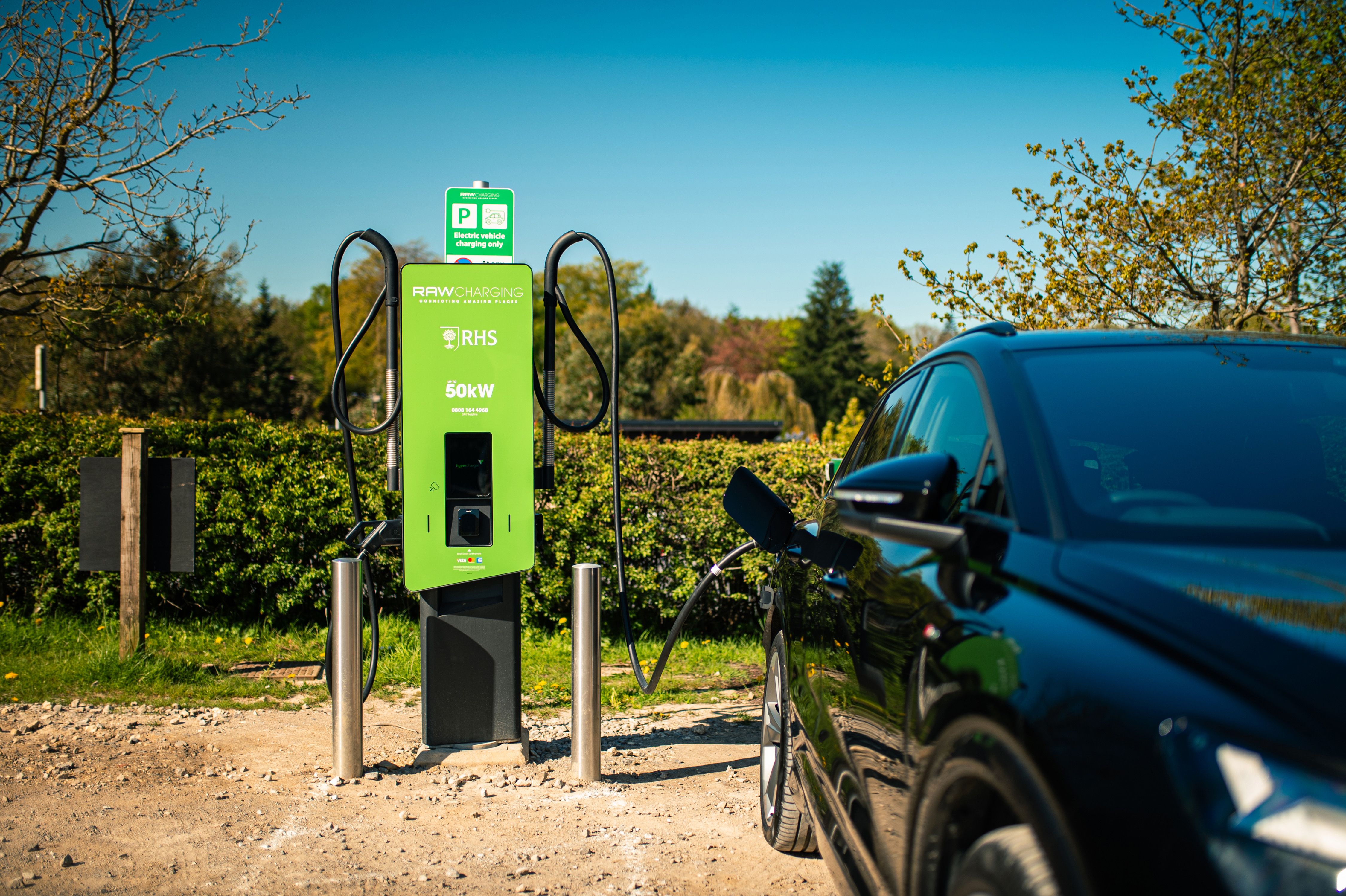 Image shows an EV Charger in RHS green, with an EV car plugged in