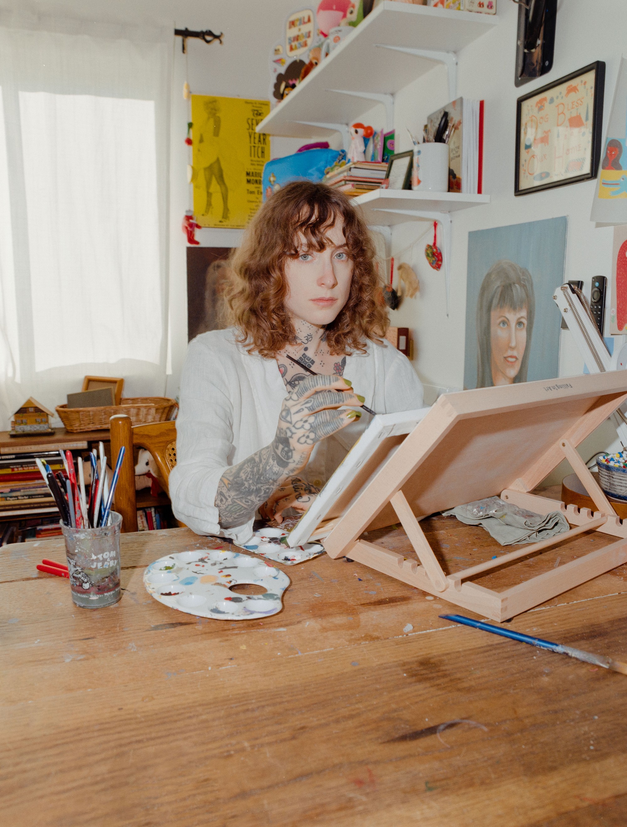Addeline Griswold aka Burger Babie painting on a tabletop easel at her Los Angeles studio desk, photographed on medium format film by Nathaniel Perales