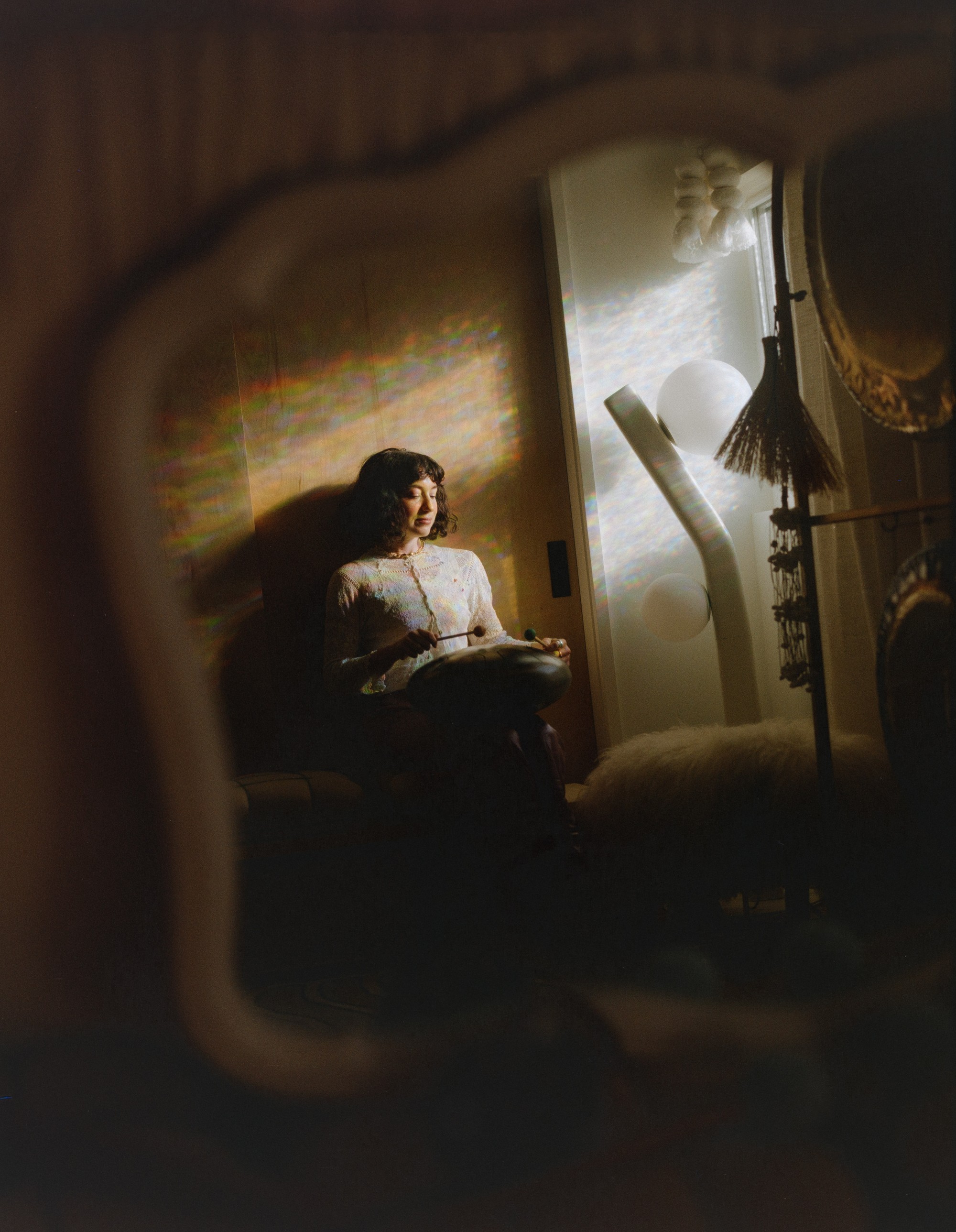 Allison Bagg framed by the edge of her gong in rainbow prism light, Los Angeles sound healing space, shot on 120 film by Nathaniel Perales