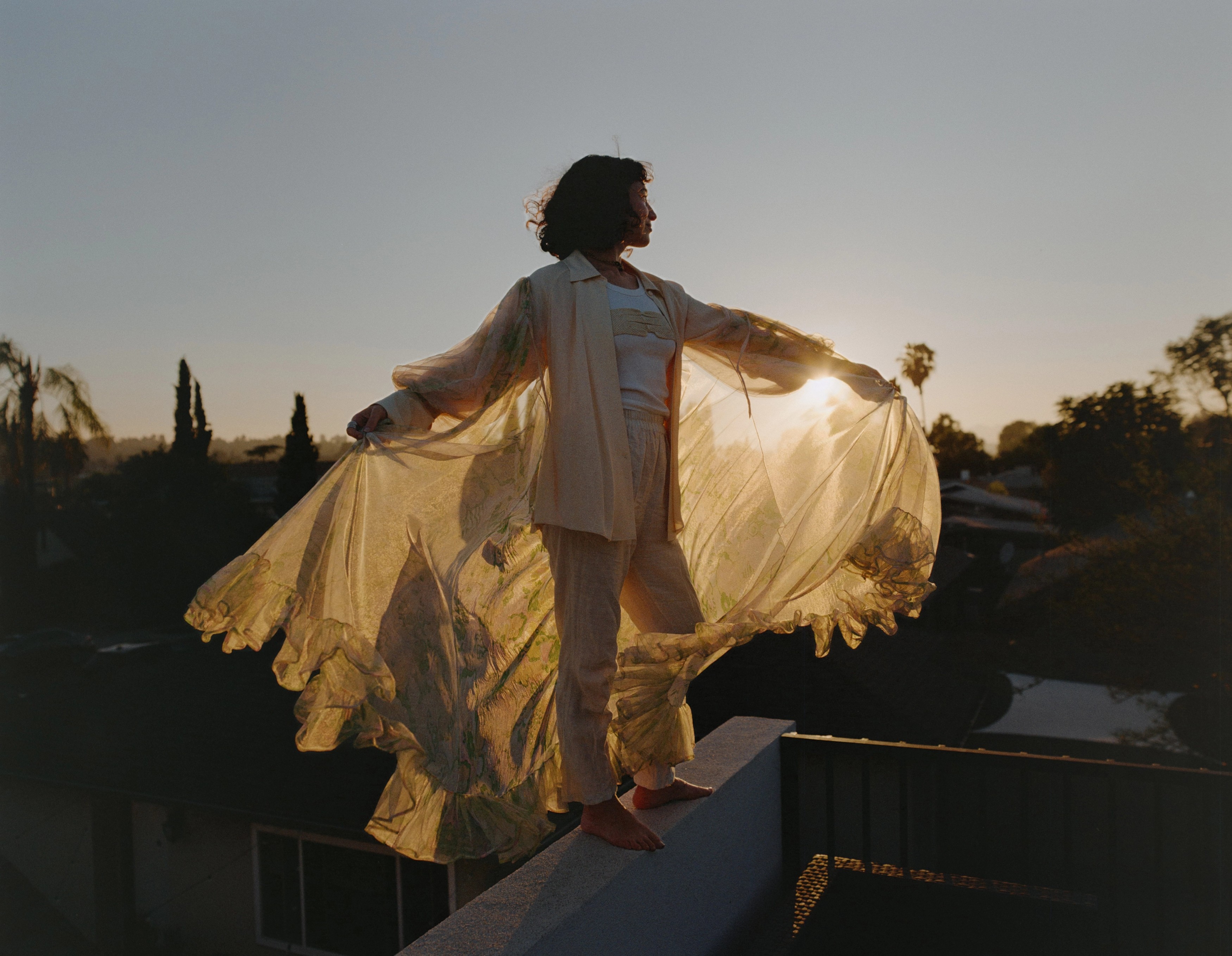 Allison Bagg on a Los Angeles rooftop at golden hour holding a flowing sheer robe open, medium format film by Nathaniel Perales