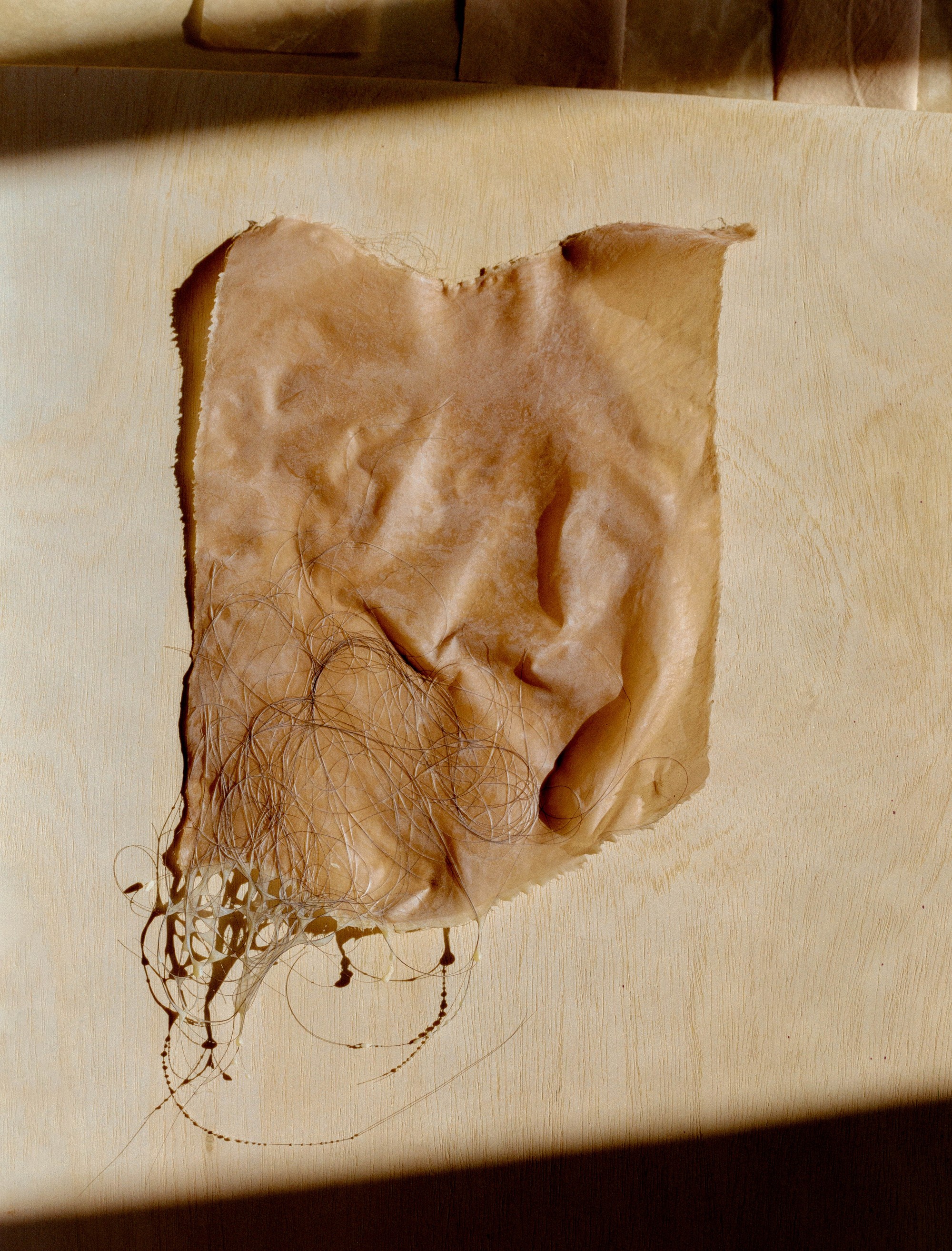 Detail of naturally dyed fabric with trailing fibers on a studio surface, Portland artist Laura Kung, medium format film by Nathaniel Perales