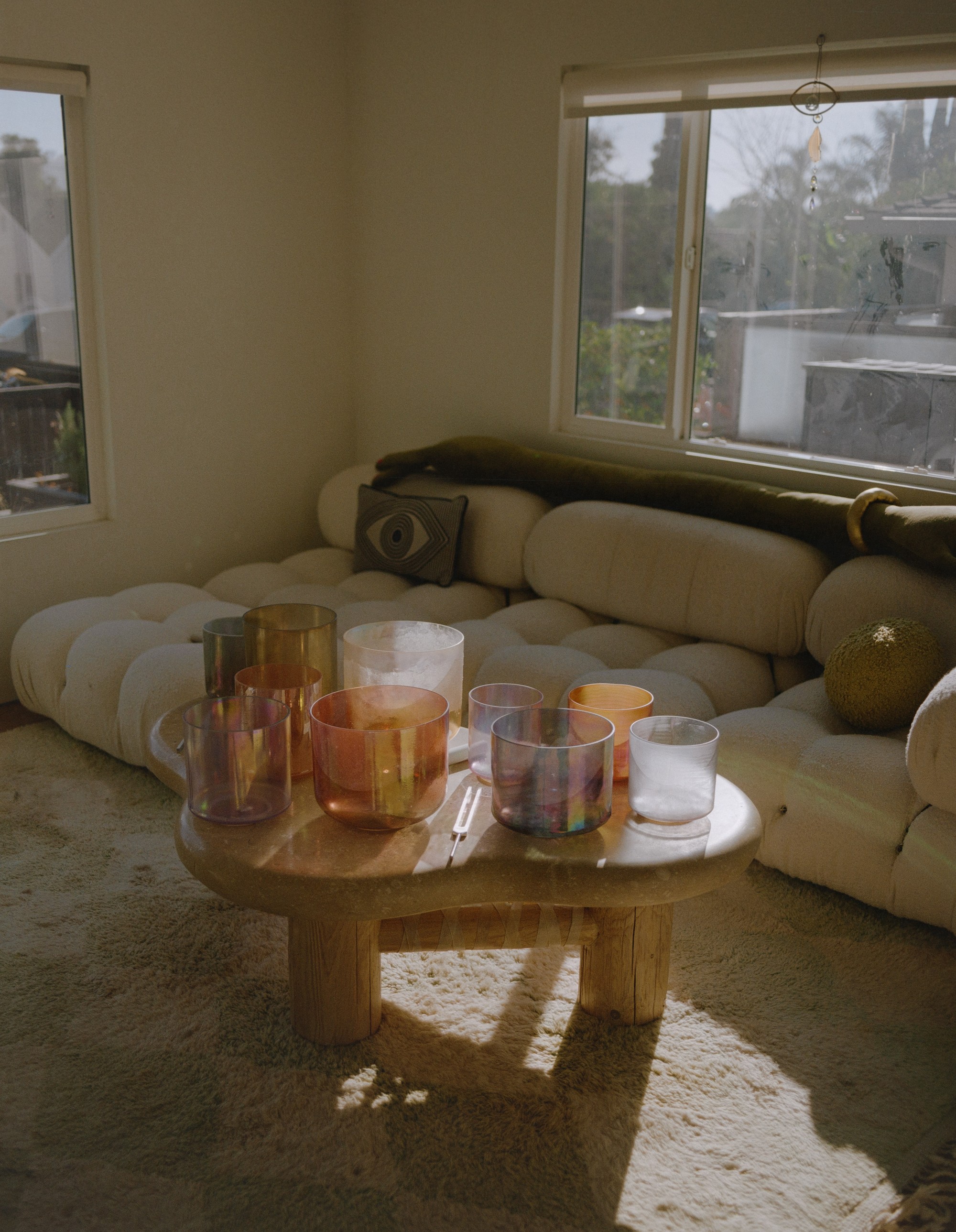 Crystal alchemy singing bowls arranged on a round marble table in Allison Bagg's Los Angeles home, shot on medium format film by Nathaniel Perales