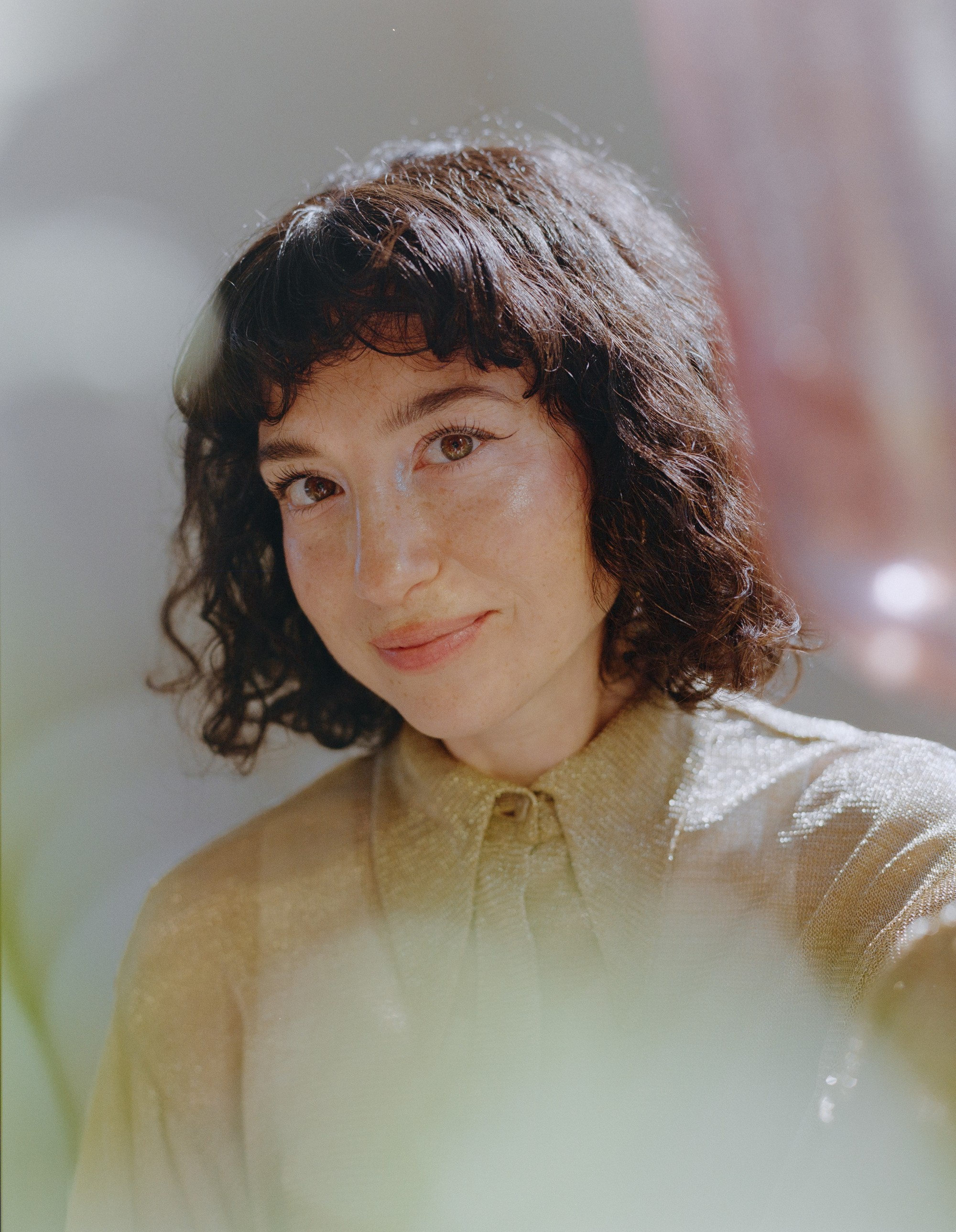 Close portrait of Allison Bagg shot through foreground blur in soft natural light, medium format film photograph by Nathaniel Perales