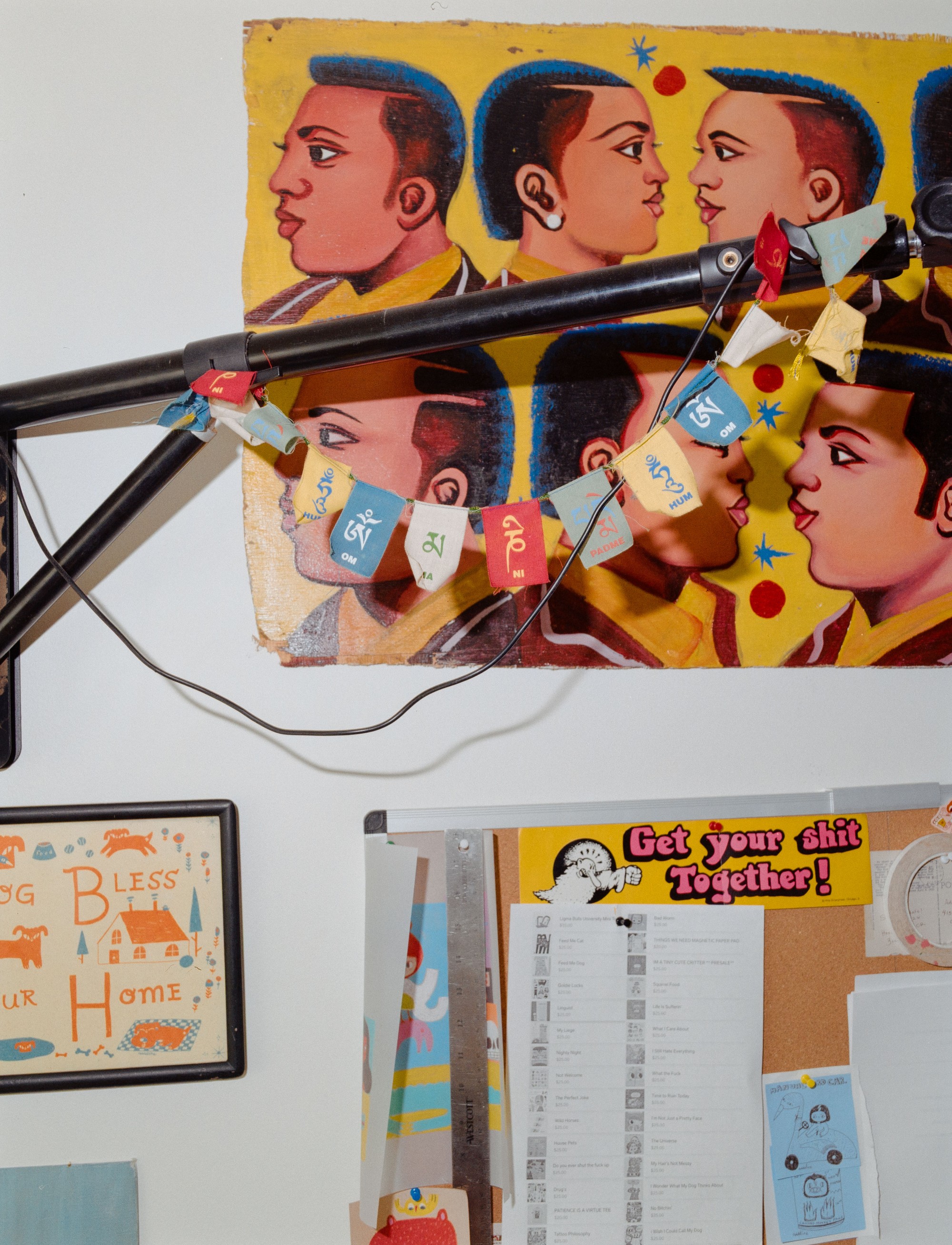 Studio wall in Addeline Griswold's Los Angeles home, featuring collected art including Tibetan prayer flags and a "Get Your Shit Together" poster, photographed on medium format film by Nathaniel Perales
