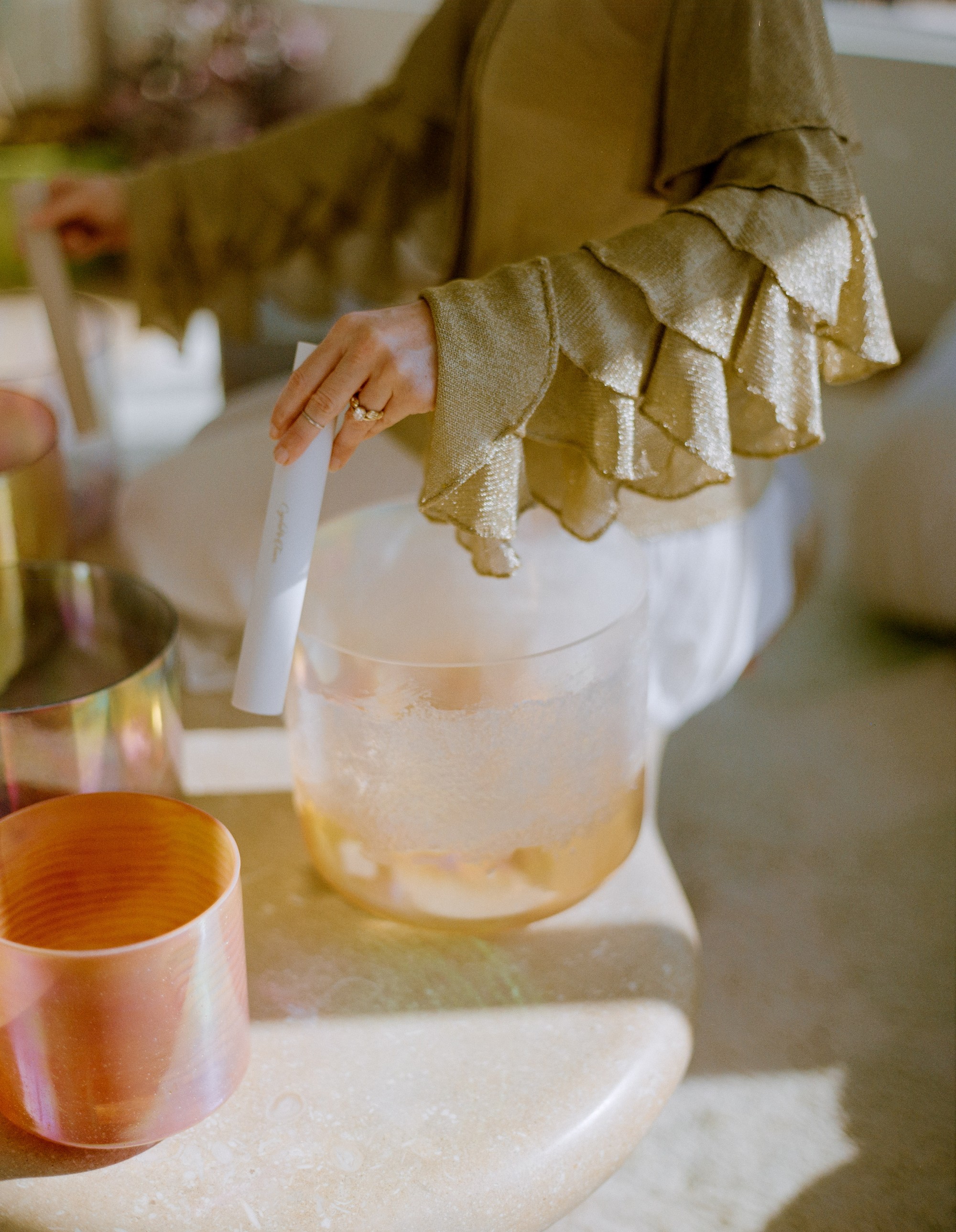 Detail of Allison Bagg's hands playing a crystal alchemy singing bowl in her Los Angeles home, shot on medium format film