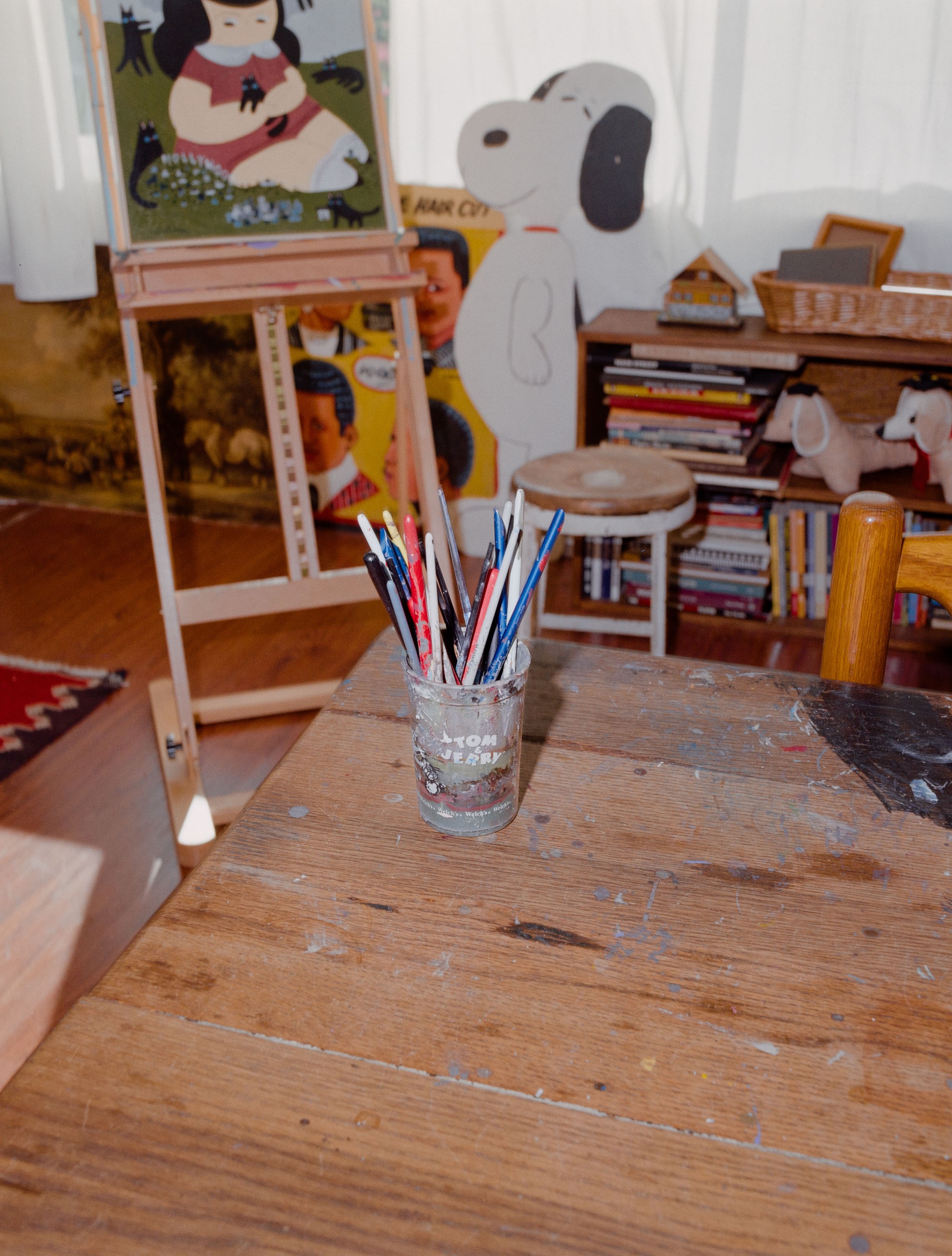 Paint-stained worktable with brushes and a Snoopy figurine in Addeline Griswold's Los Angeles studio, shot on 120 film by Nathaniel Perales